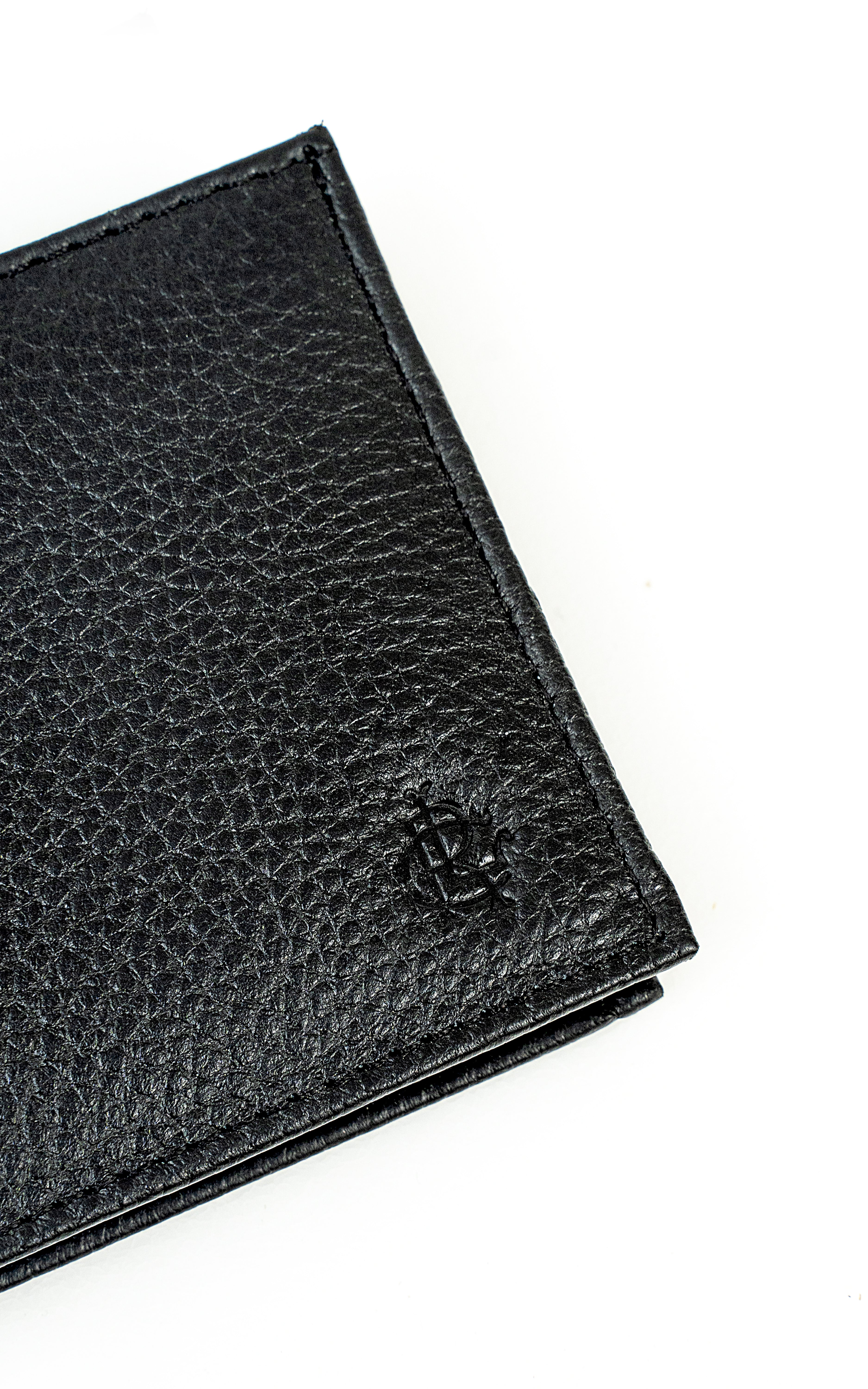 Black leather wallet corner close-up with textured grain and engraved logo