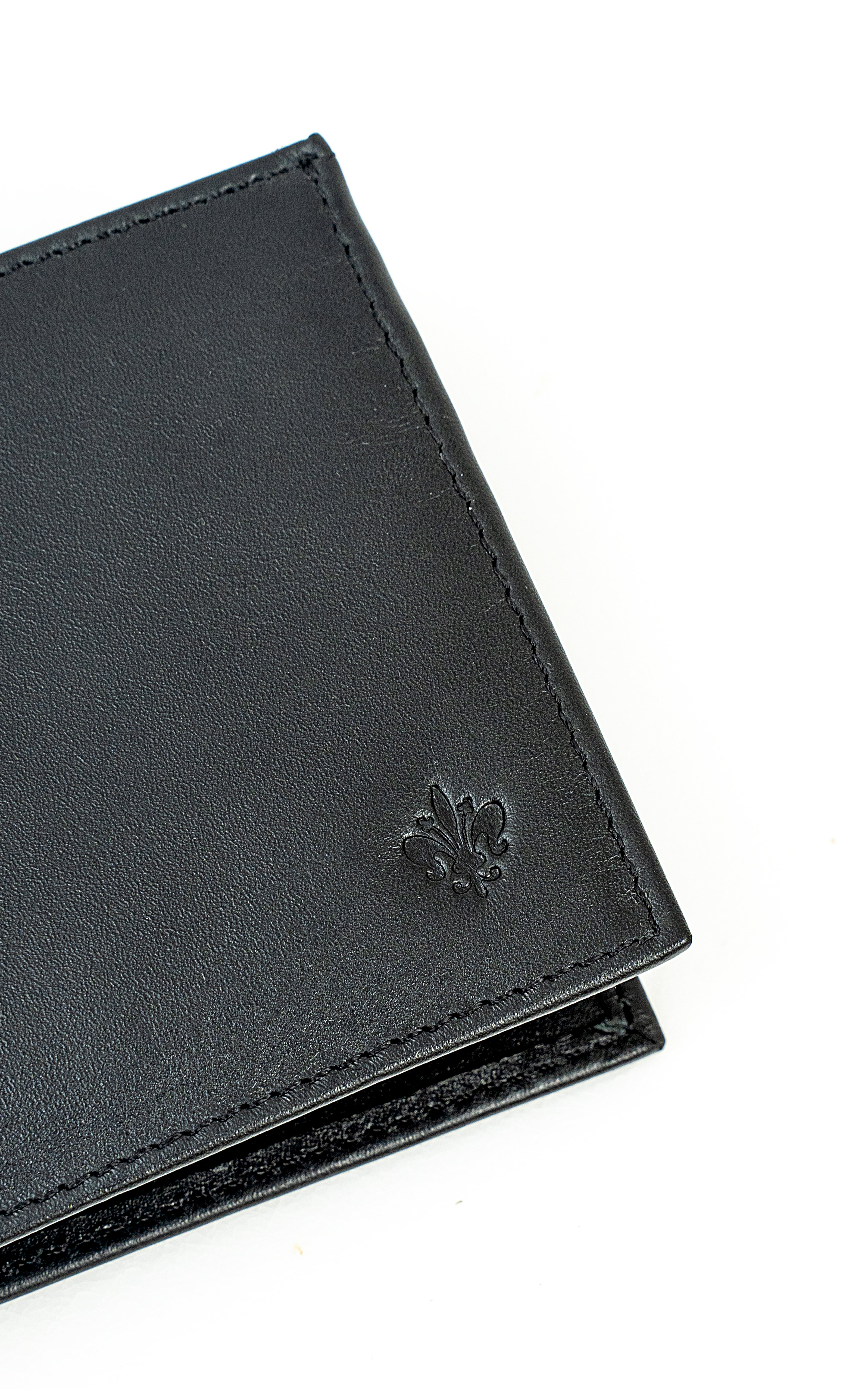 Black leather wallet corner with embossed clover detail and contrast stitching