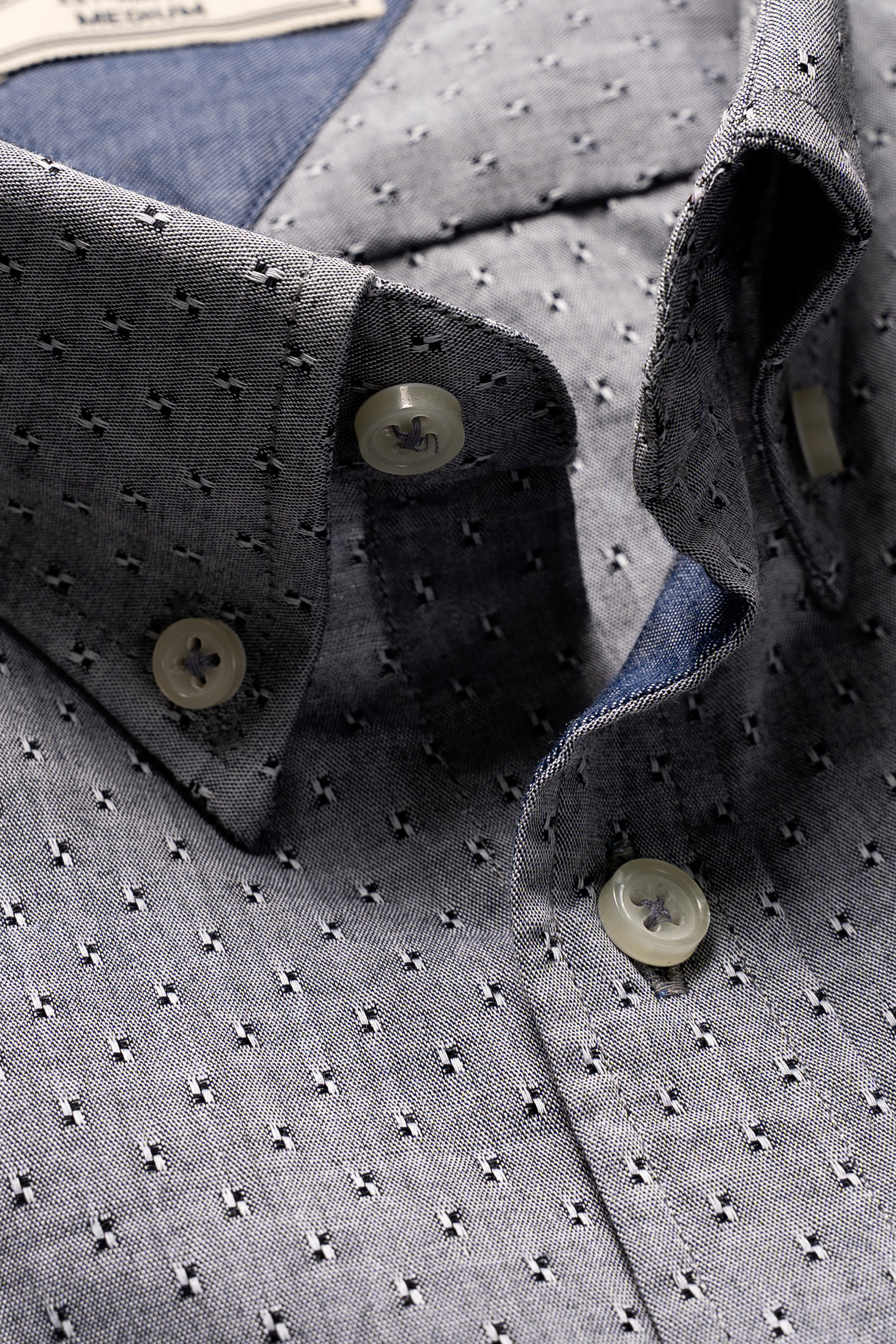 Close-up of grey patterned button-up shirt collar and front placket with buttons