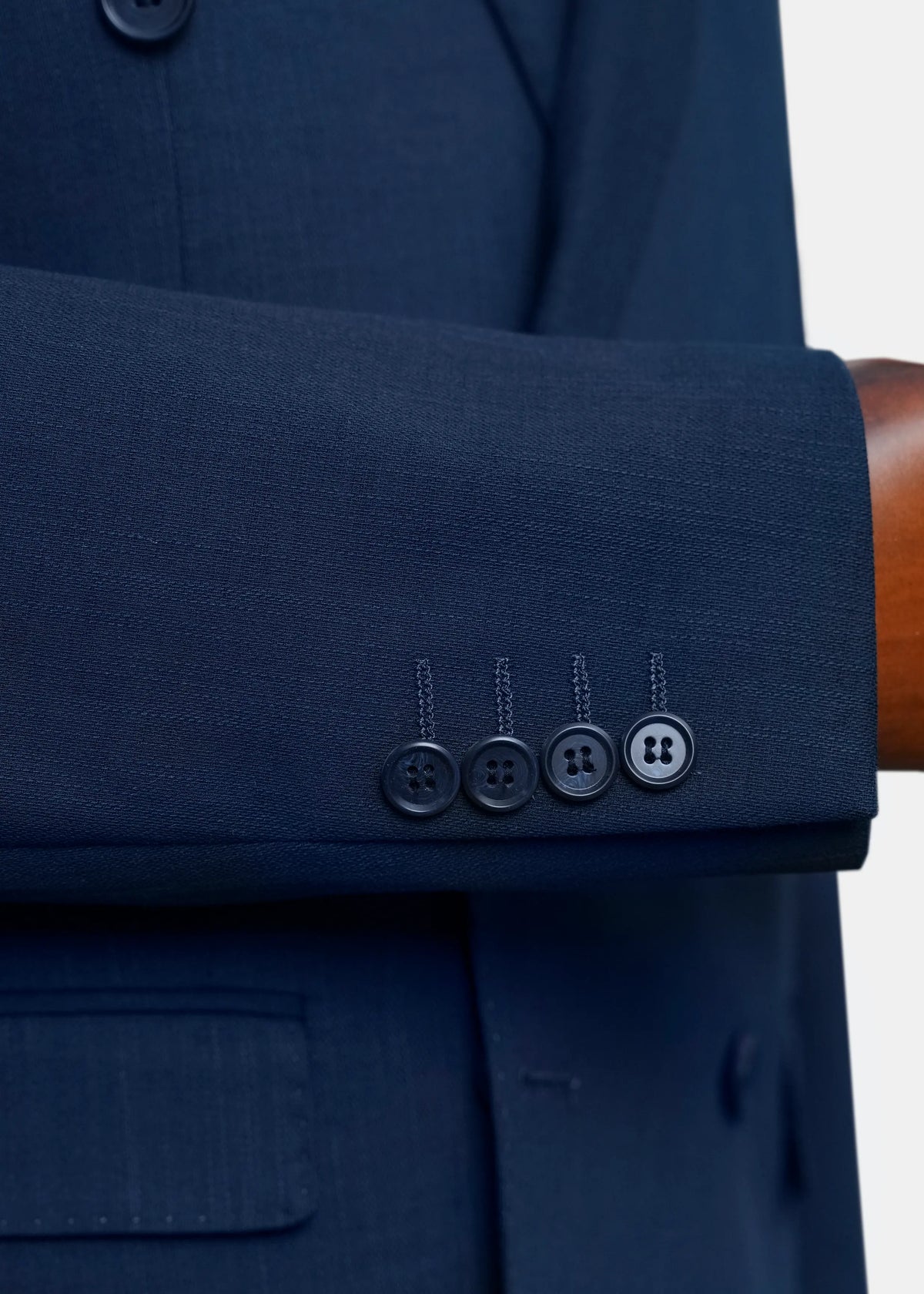 Navy coat cuff with four-button closure and stitched sleeve hem