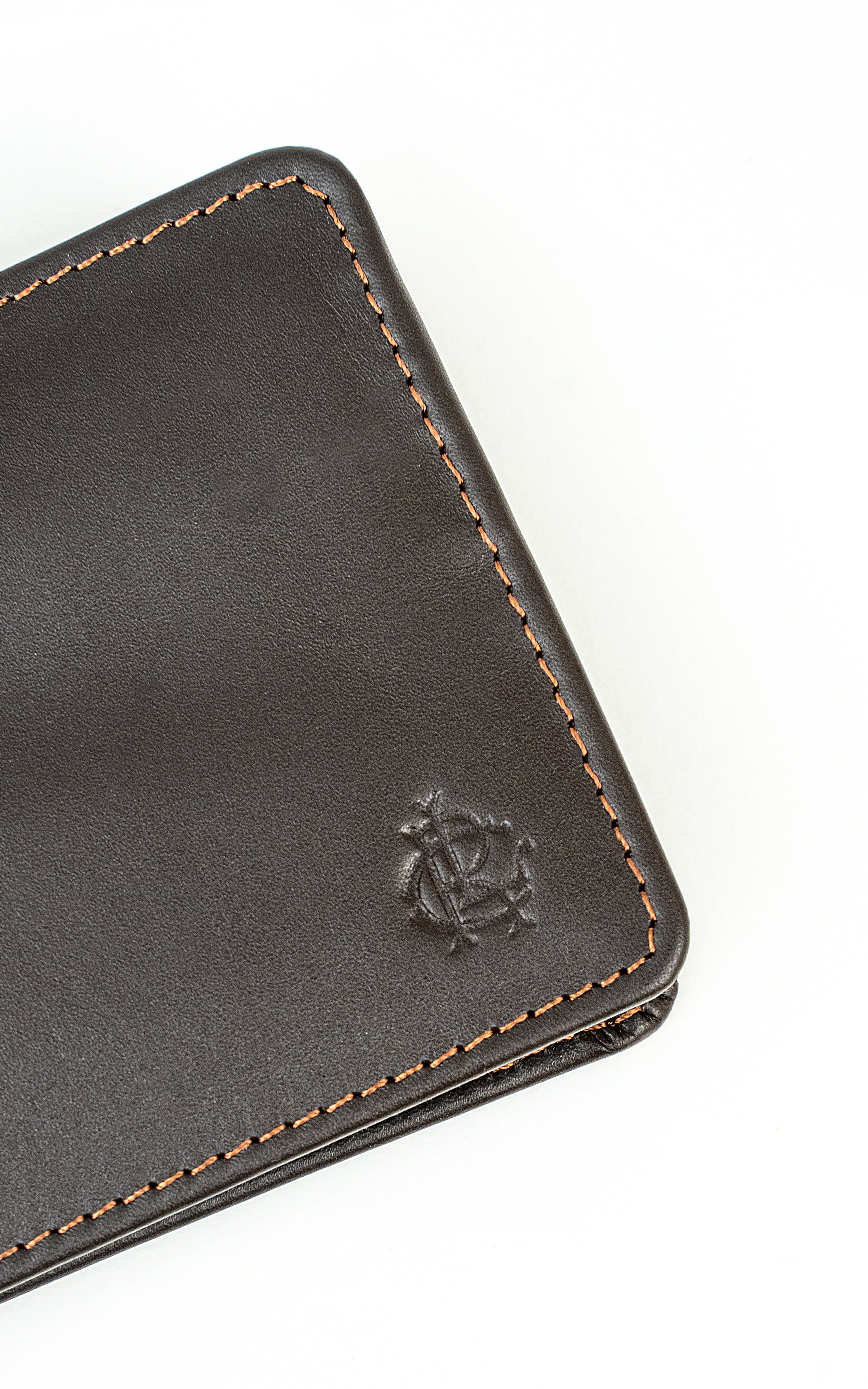 Brown leather wallet corner close-up with embossed emblem and contrast edge stitching