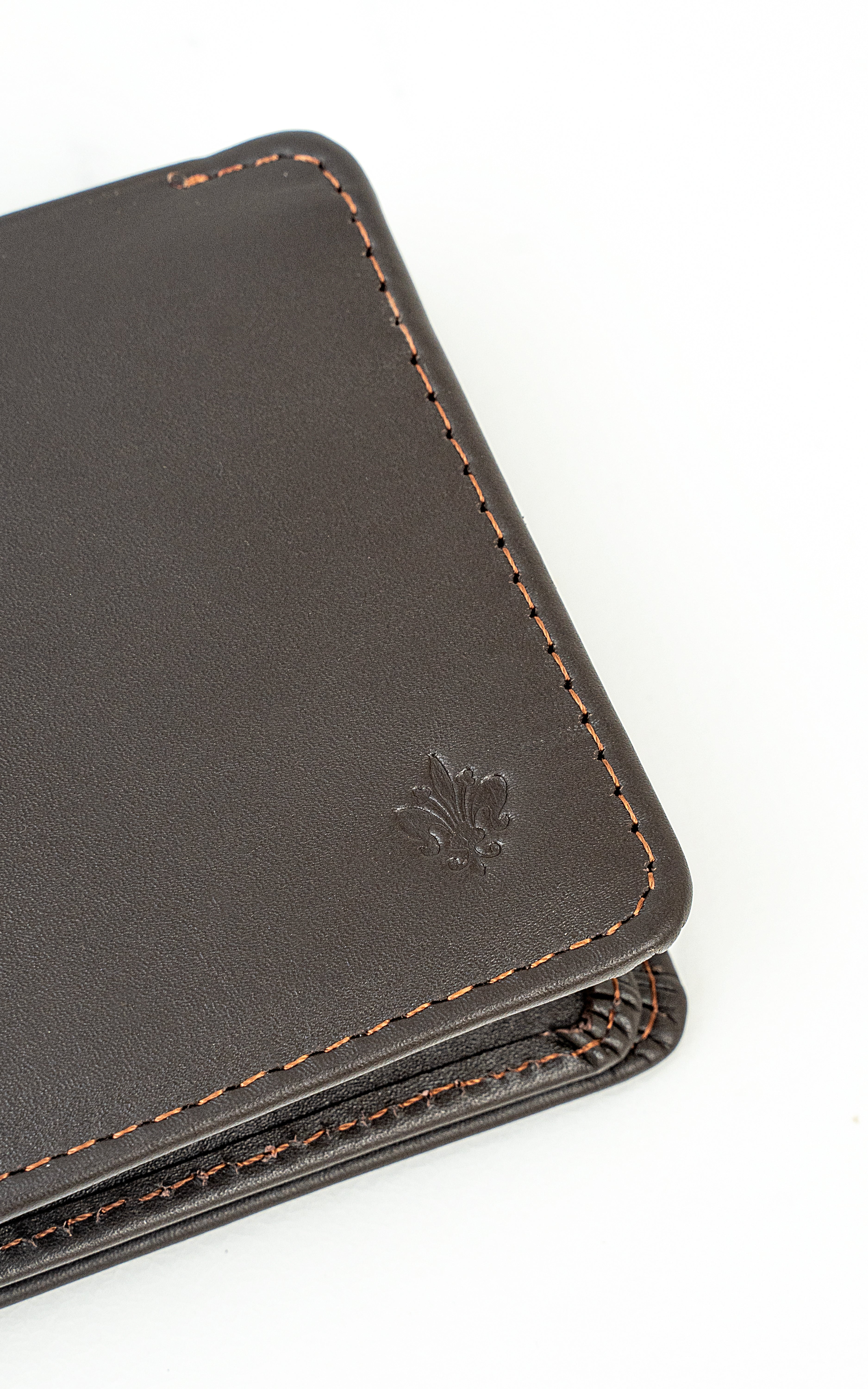 Dark brown wallet corner close-up with embossed emblem and contrast stitching
