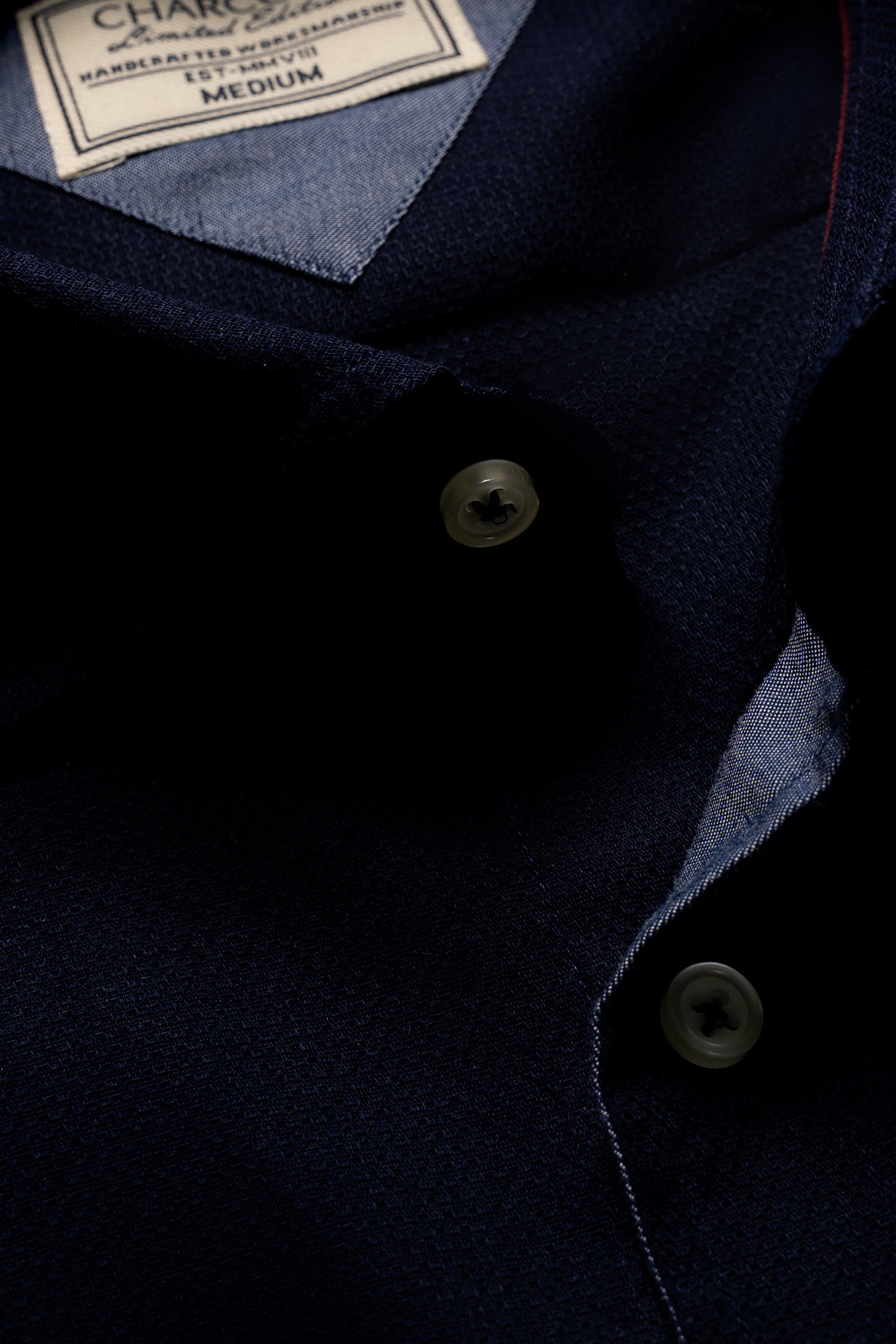 Navy blue dress shirt close-up with collar label and metal buttons