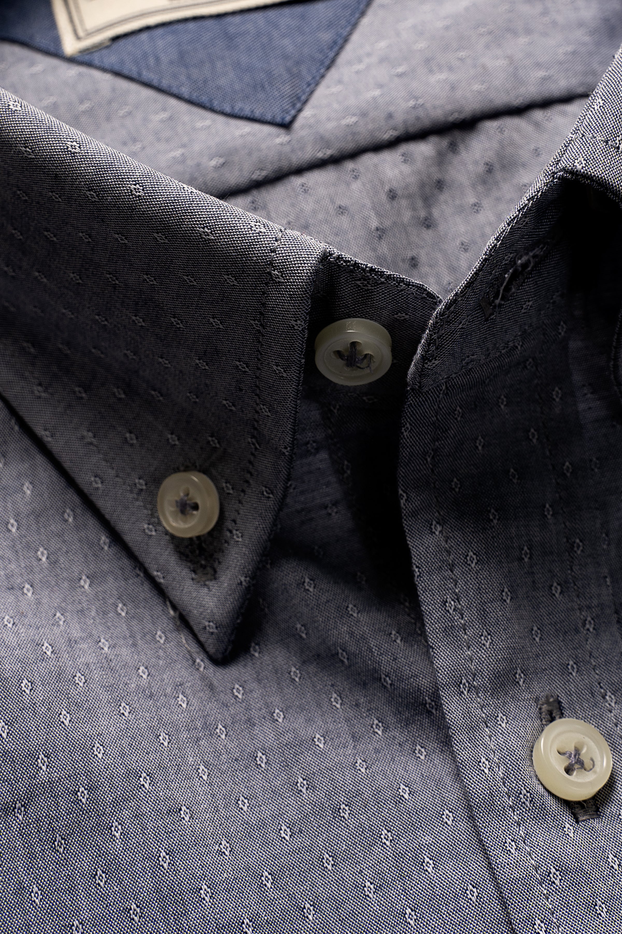 Grey shirt collar and button placket close-up with subtle dot pattern