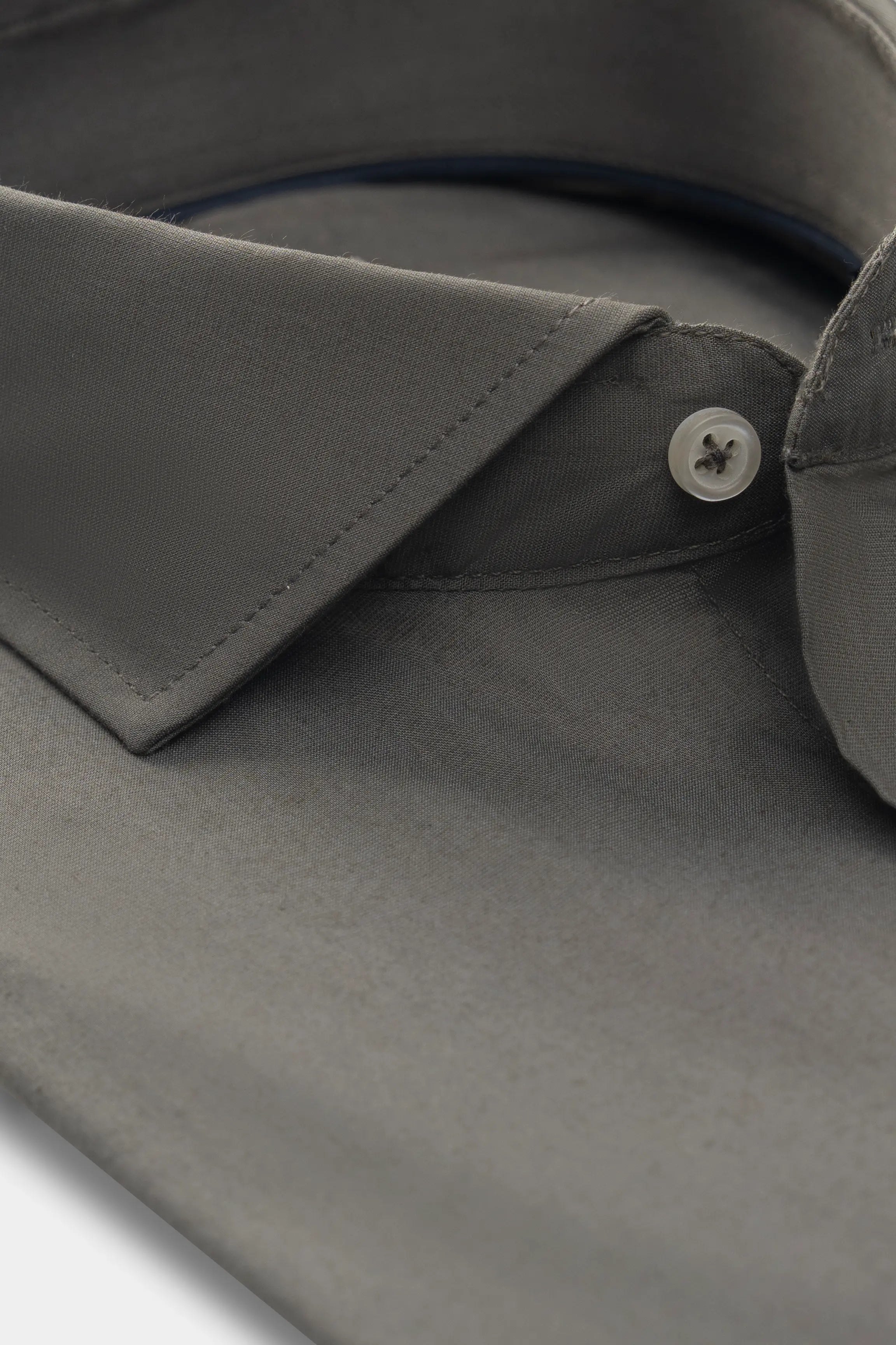 Dark olive-green shirt collar detail with white button and front placket