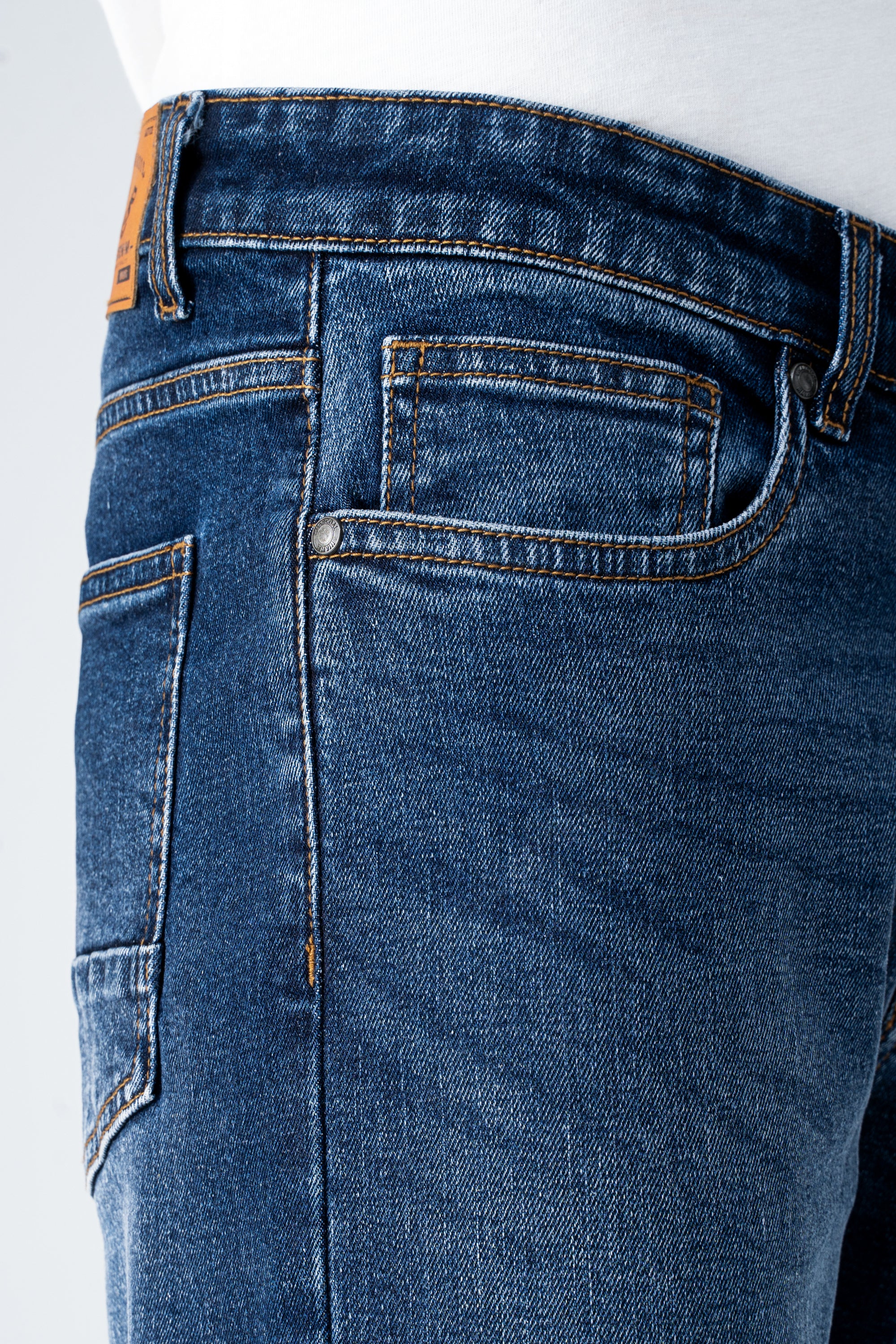 Dark blue denim jeans waist and front pocket detail with button and belt loops