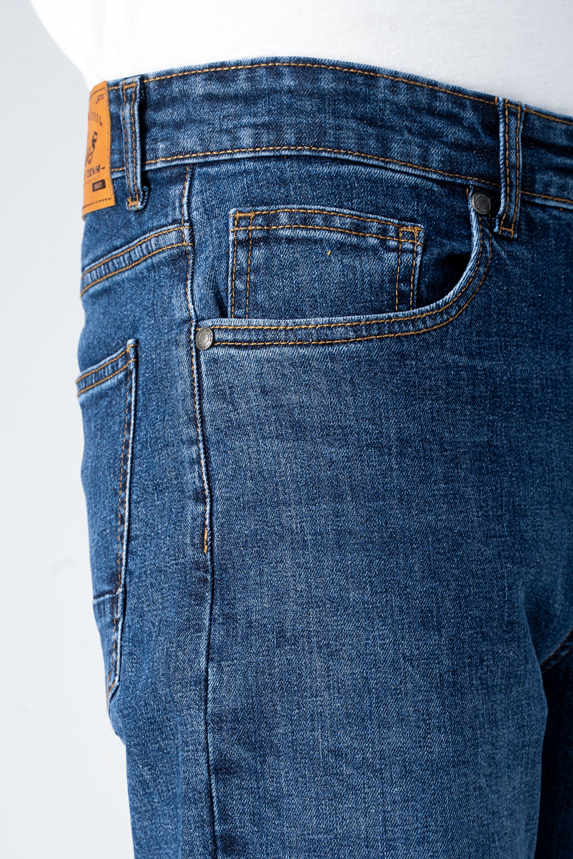 Mid blue denim jeans close-up of waistband, belt loops, and front pocket stitching.