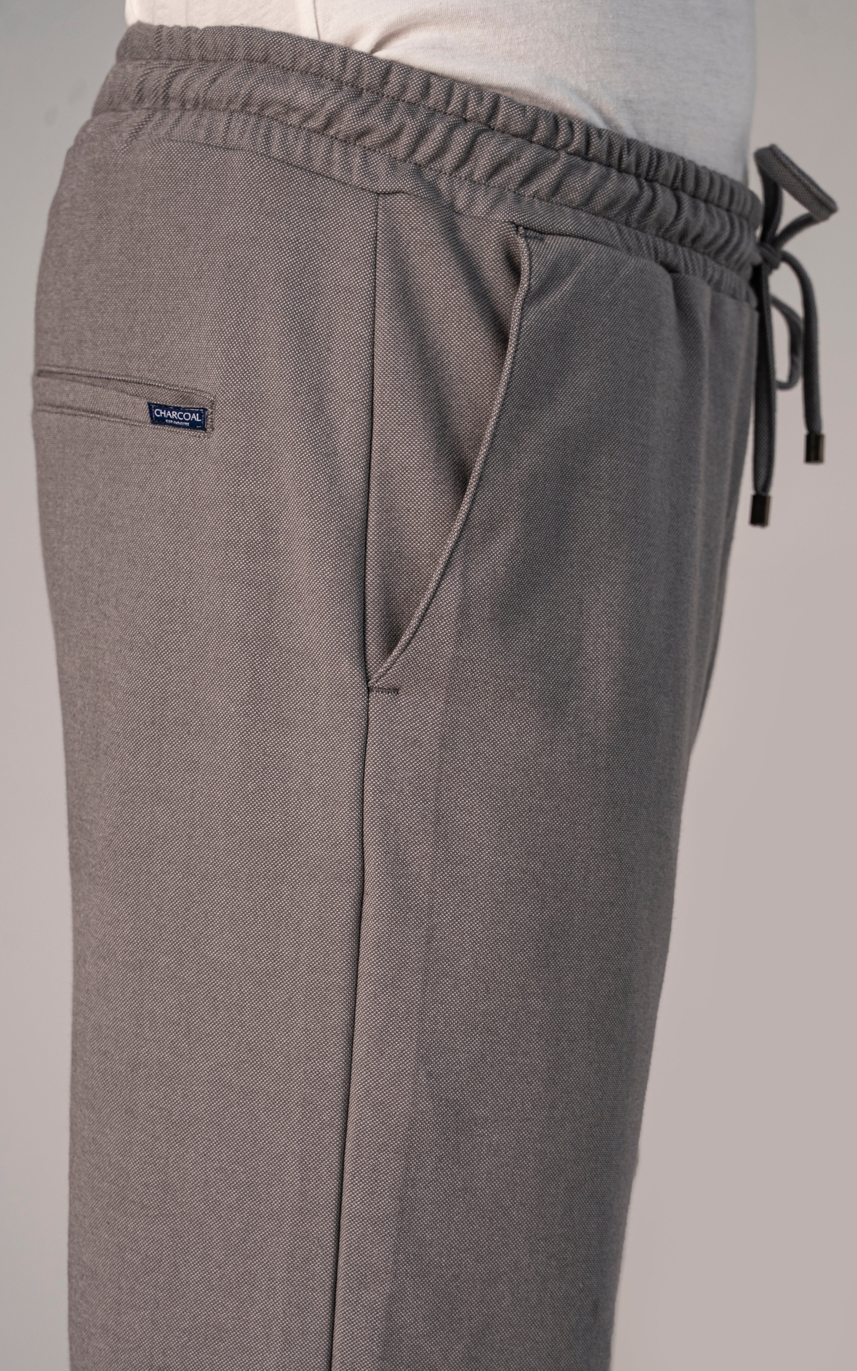 Grey melange trouser close-up: drawstring waist, side pocket, embroidered logo patch
