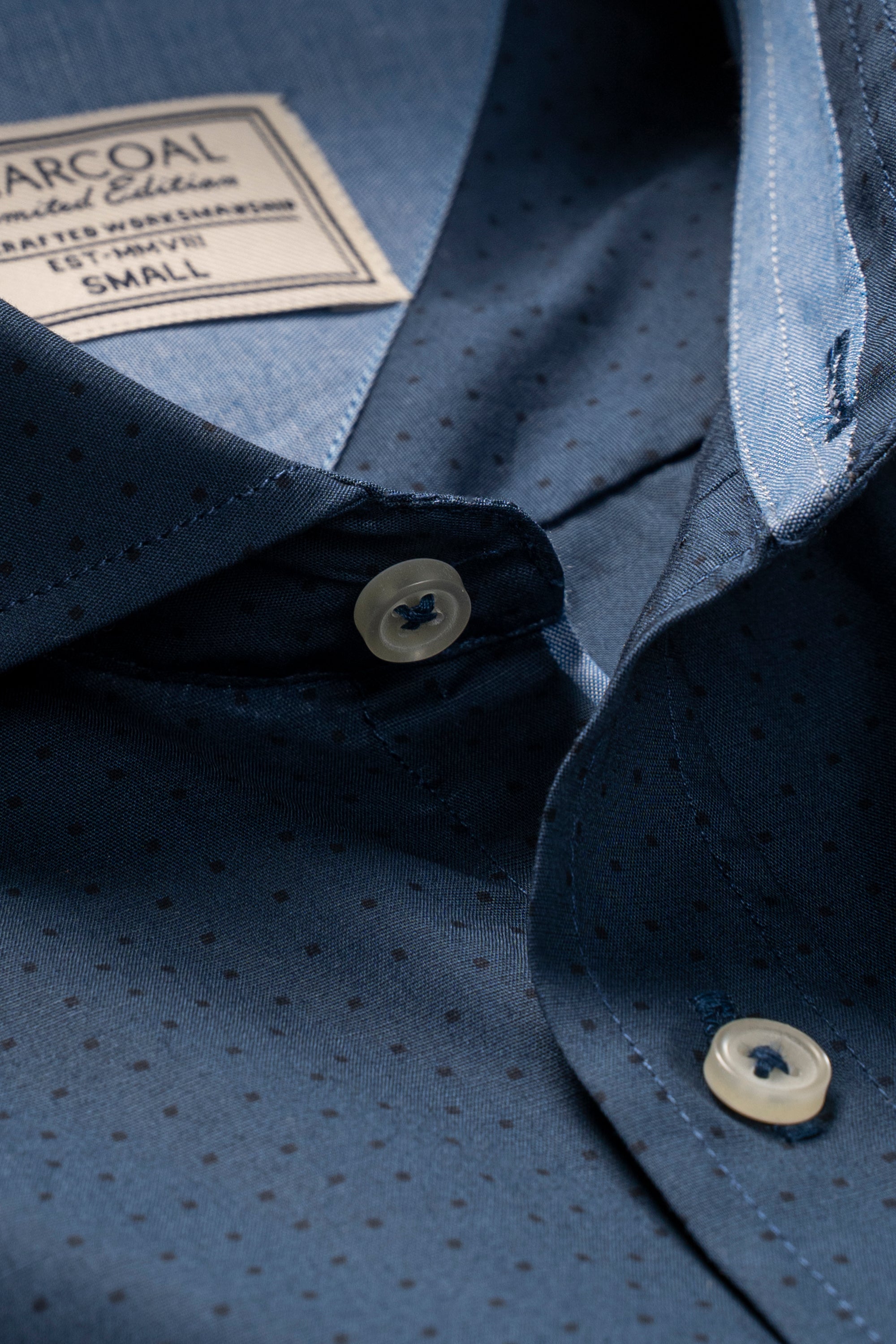 Blue shirt close-up showing fabric texture and white button at placket