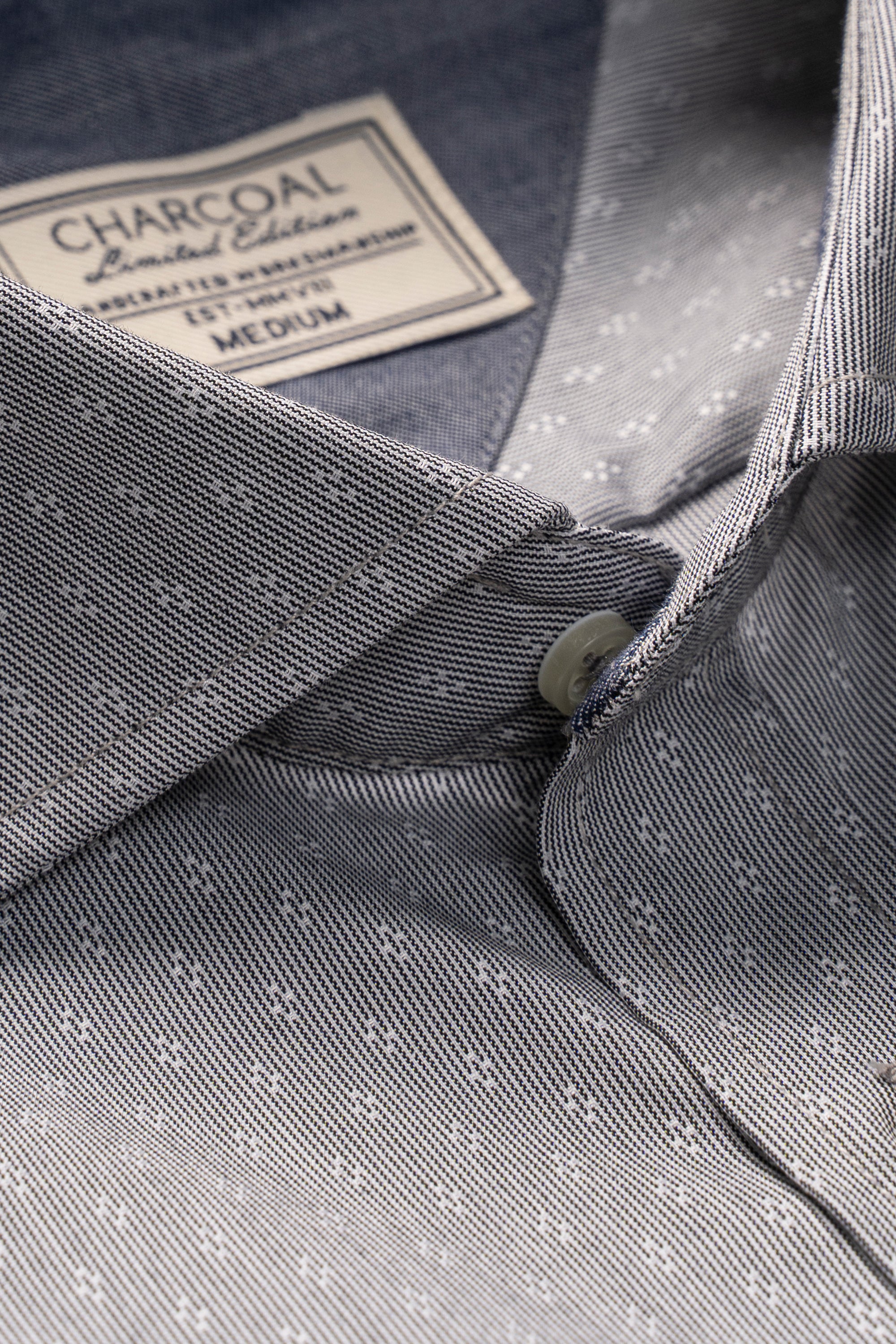 Grey button-up shirt collar detail with subtle pattern and button