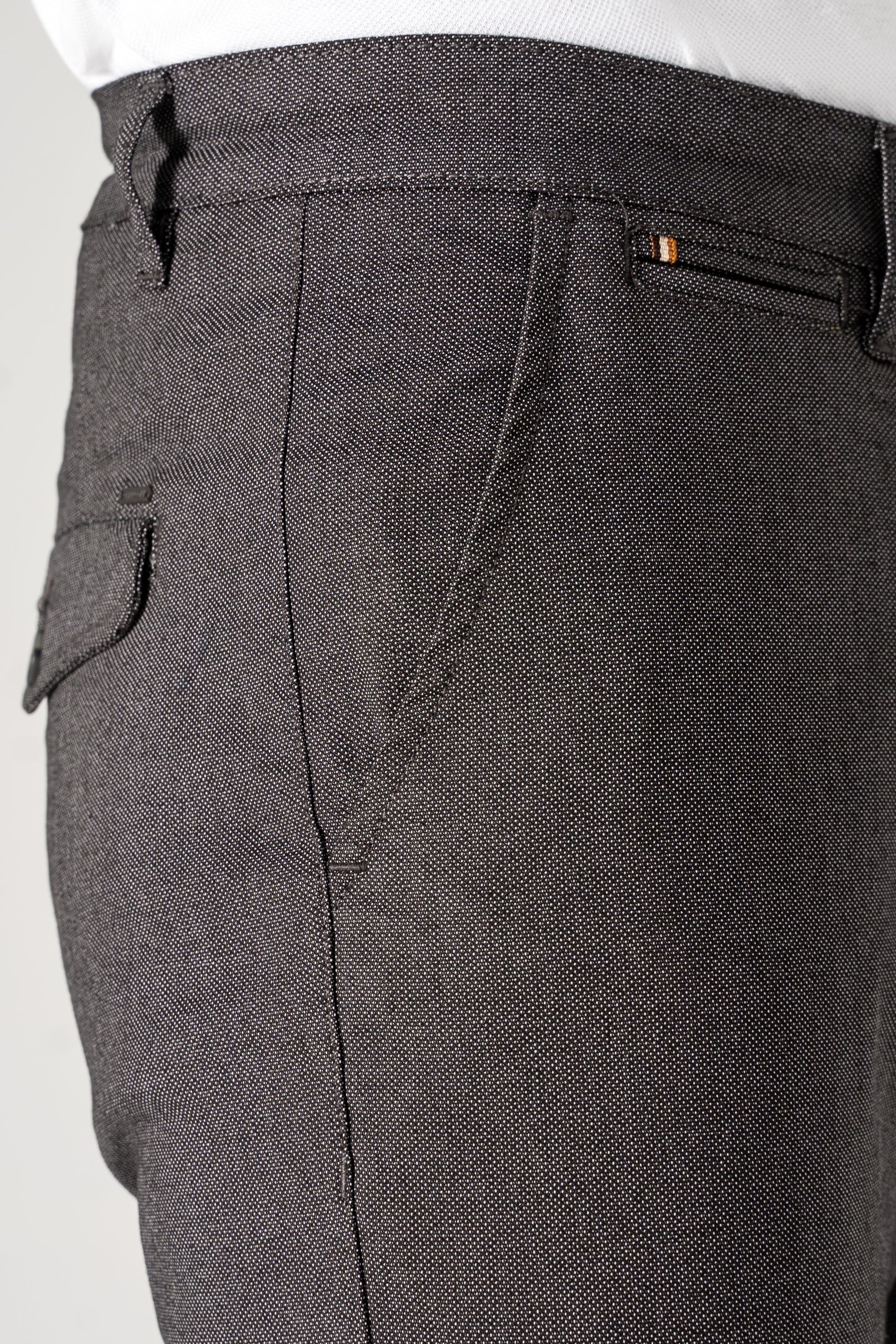 Close-up of charcoal textured pants pockets with stitched seams and waistband tab