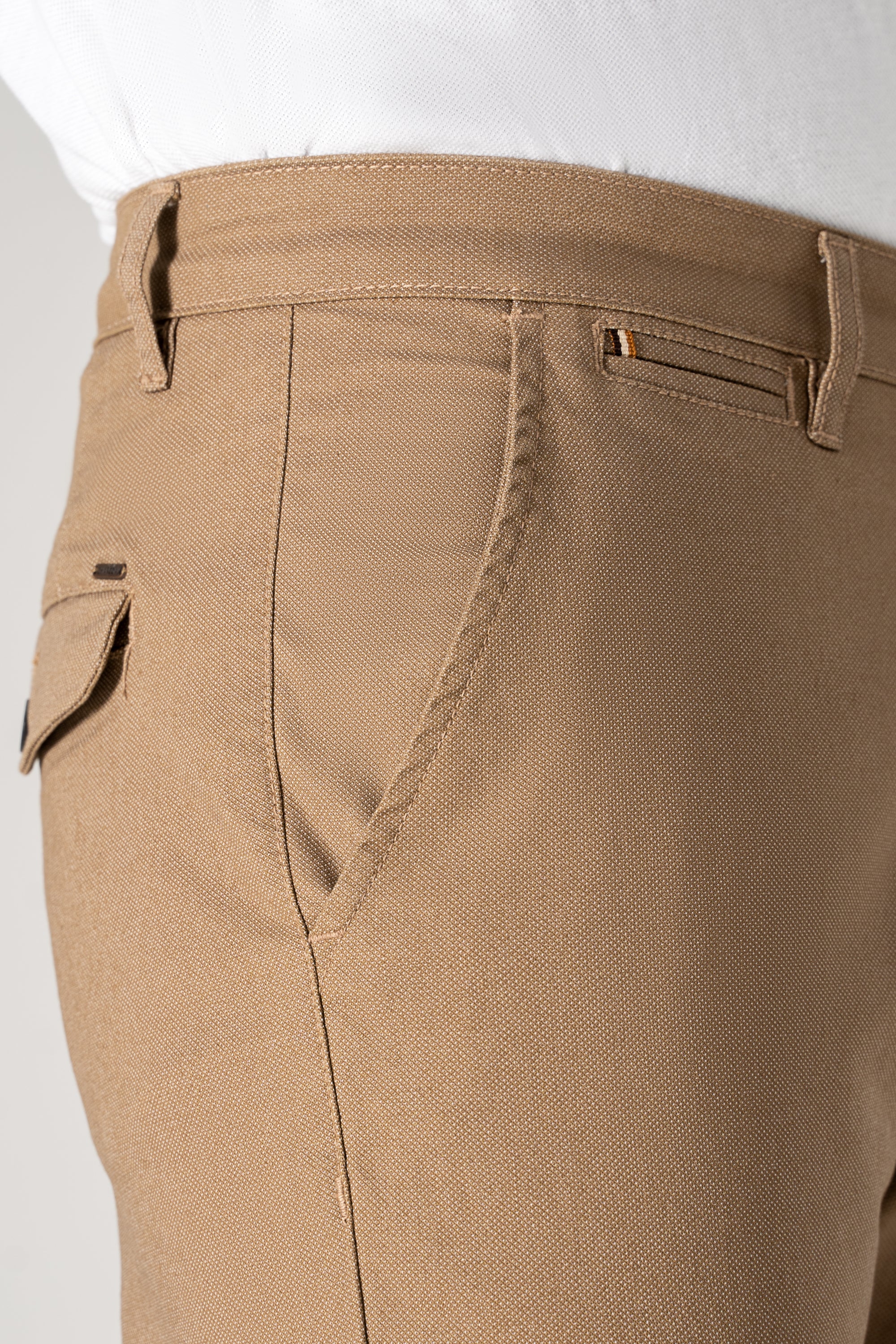 Khaki textured pants close-up: front pocket, belt loop, and button