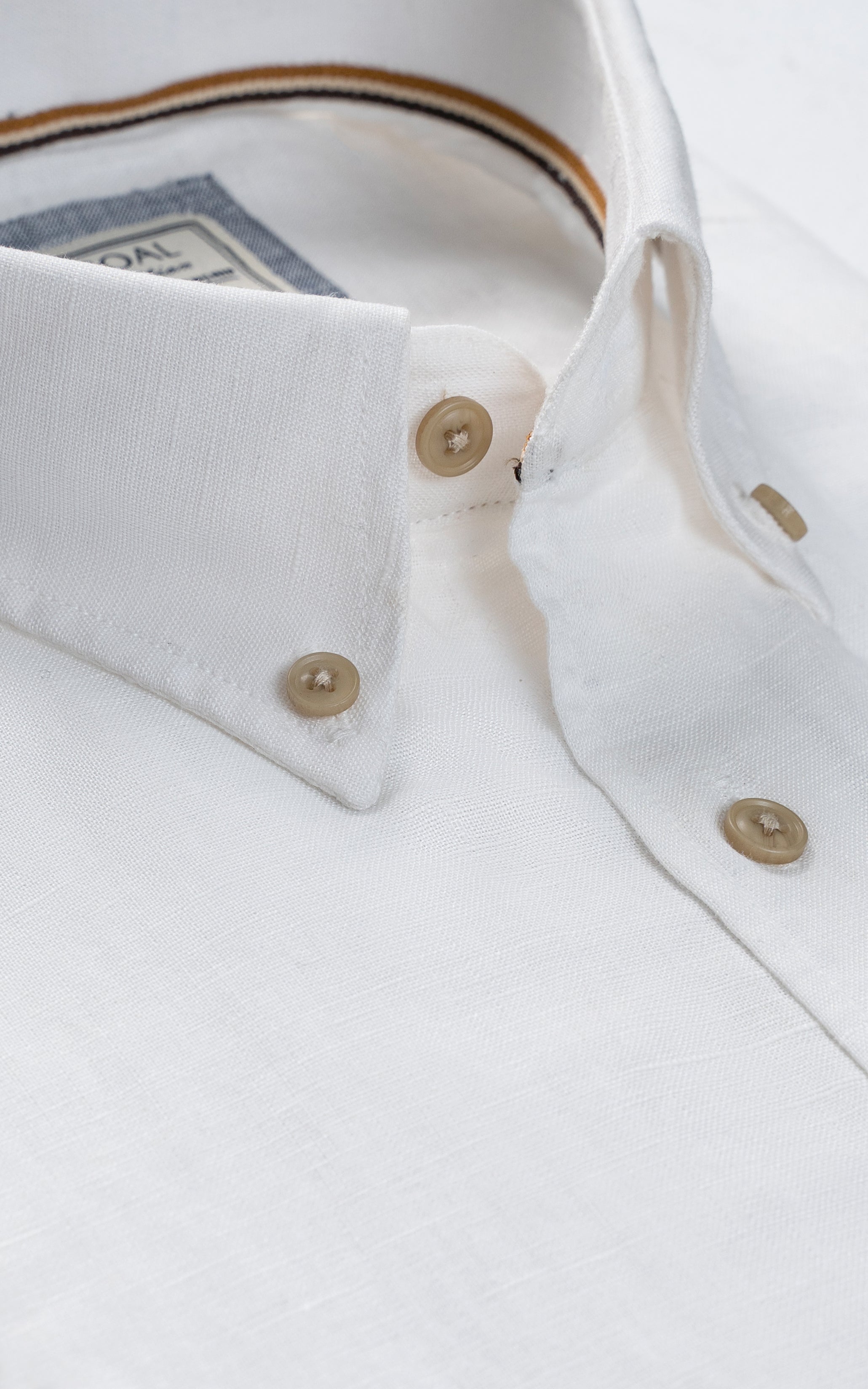 Off-white linen shirt collar and cuffs with gold buttons, close-up detail