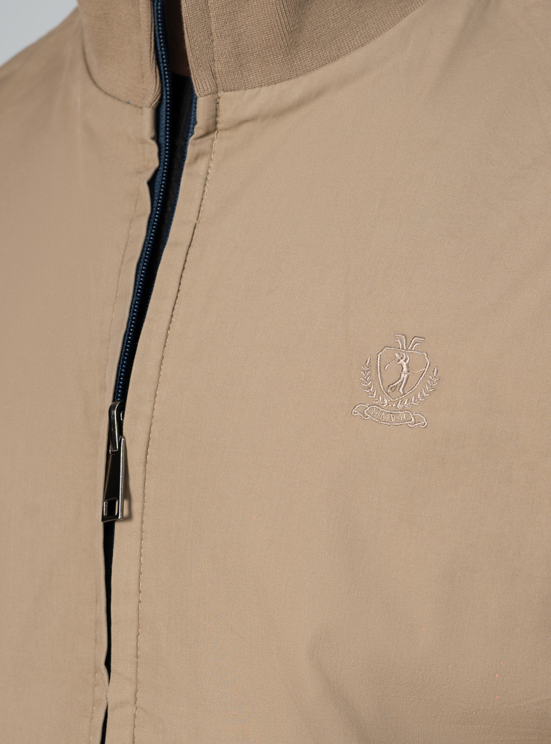 Reversible tipping jacket detail: khaki fabric, zip front edge, subtle crest logo