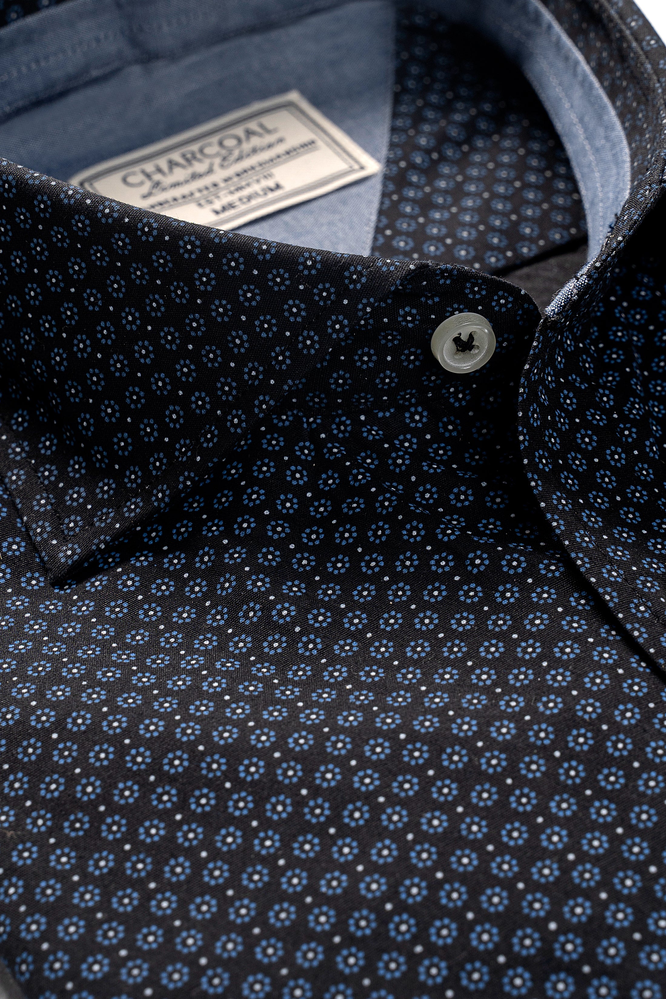 Men's dark patterned dress shirt collar detail with button and inner label