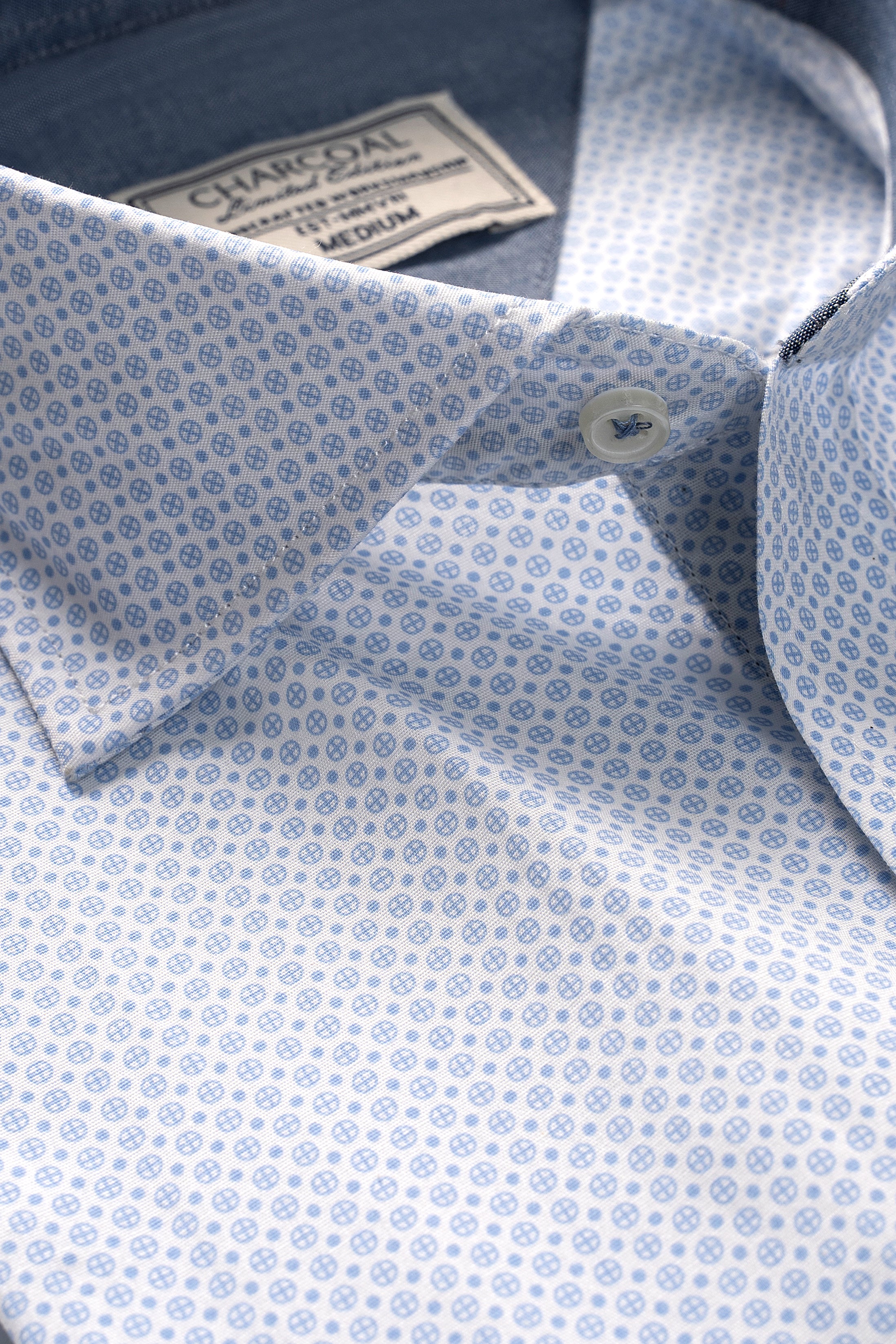 Dress shirt collar close-up, pale blue micro-pattern, branded inner label