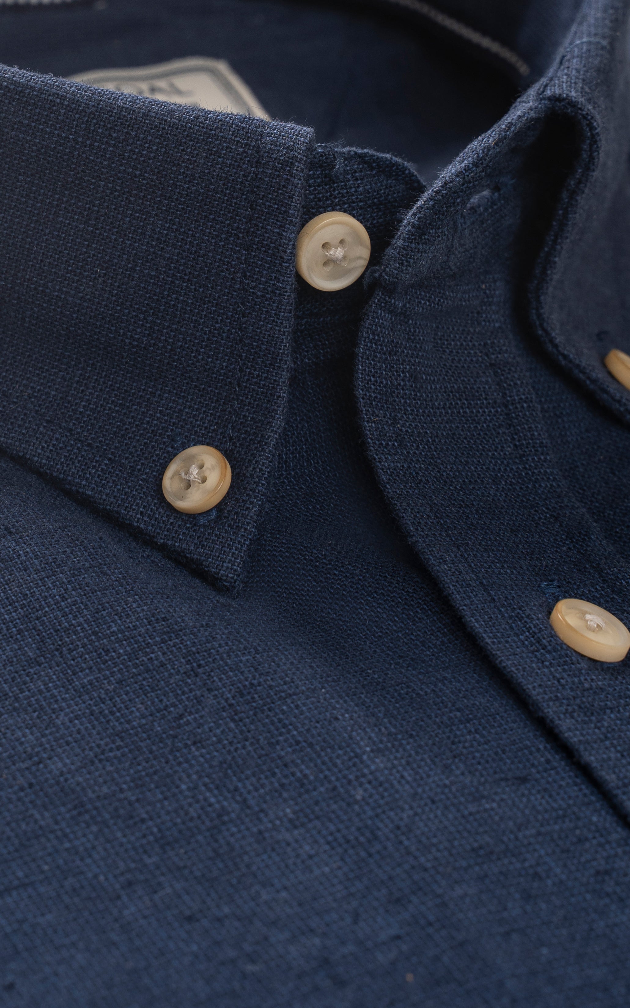 Navy linen shirt placket with round beige buttons and pointed collar