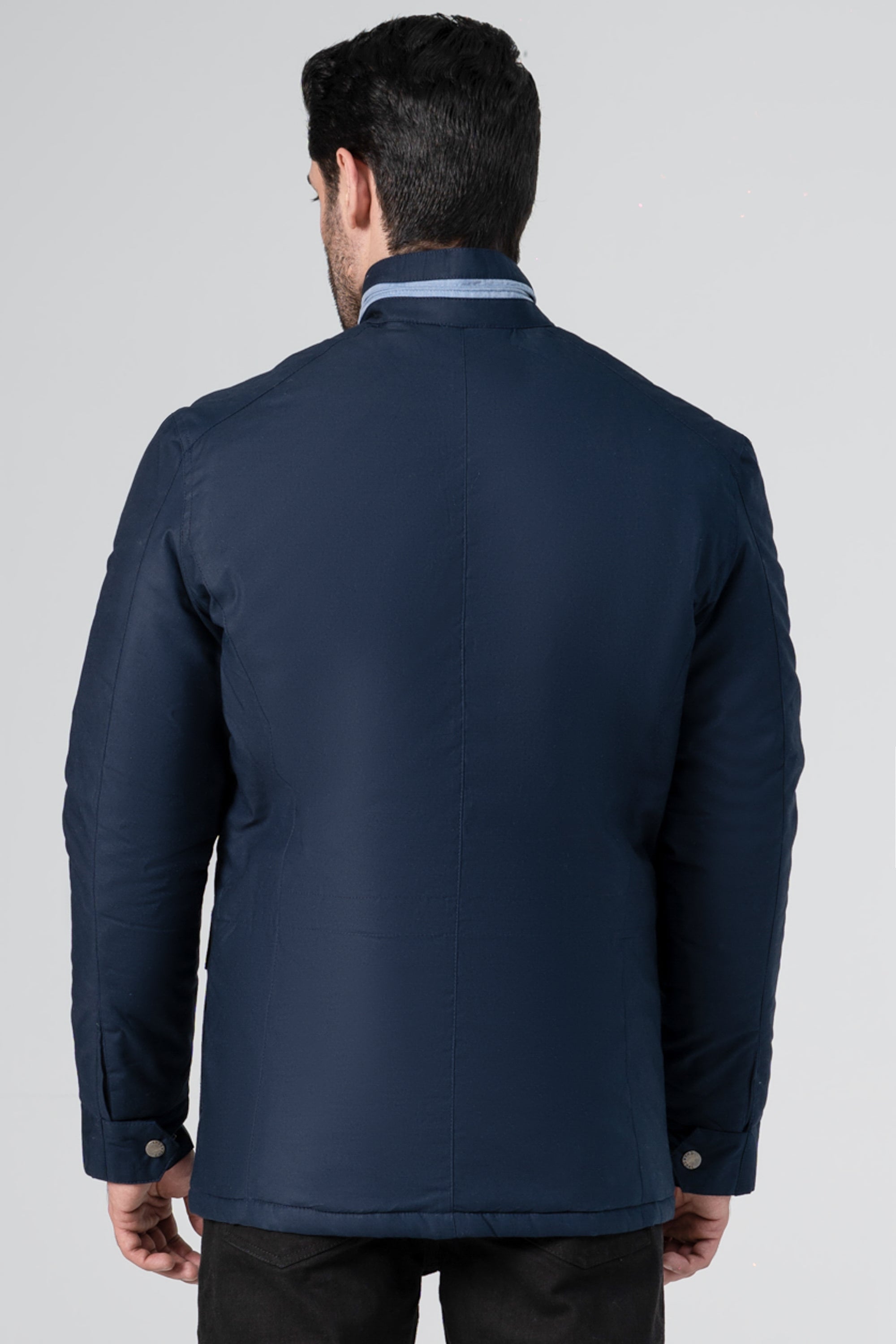 Back view of navy puffer jacket with stand collar and buttoned pockets.