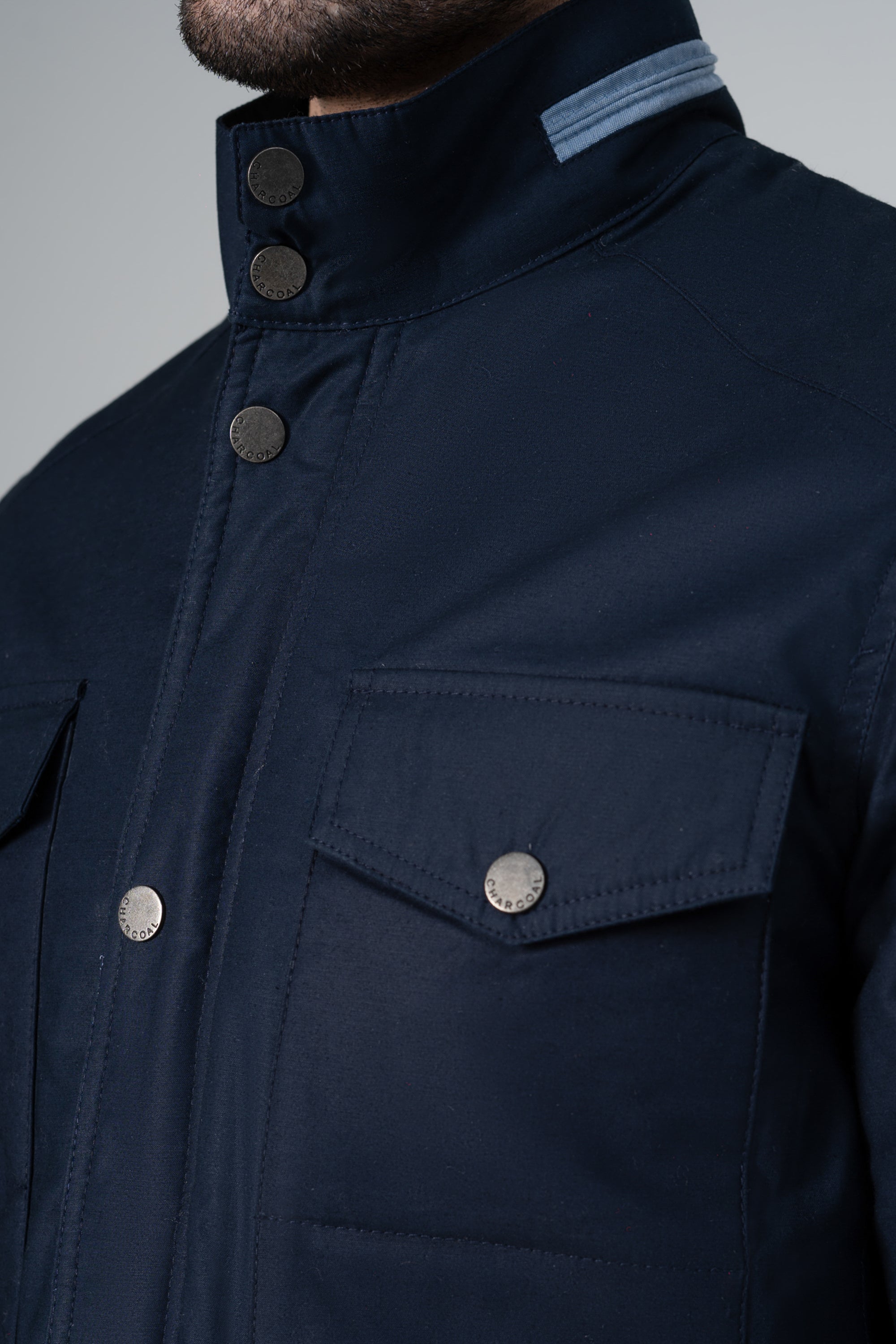 Navy puffer jacket close-up: stand collar snaps and flap chest pocket.