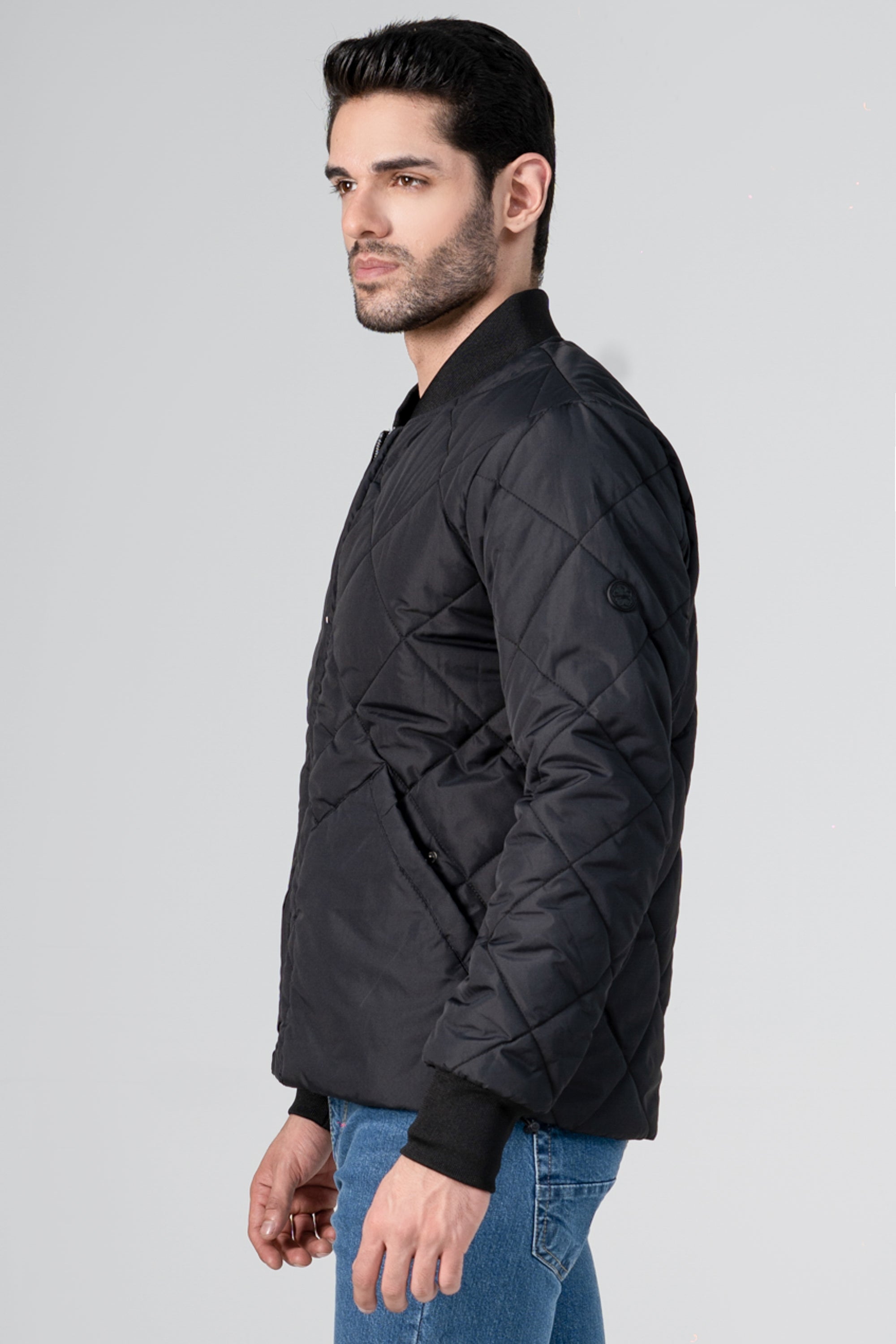 Quilted black bomber jacket, side profile with zipper and ribbed hem