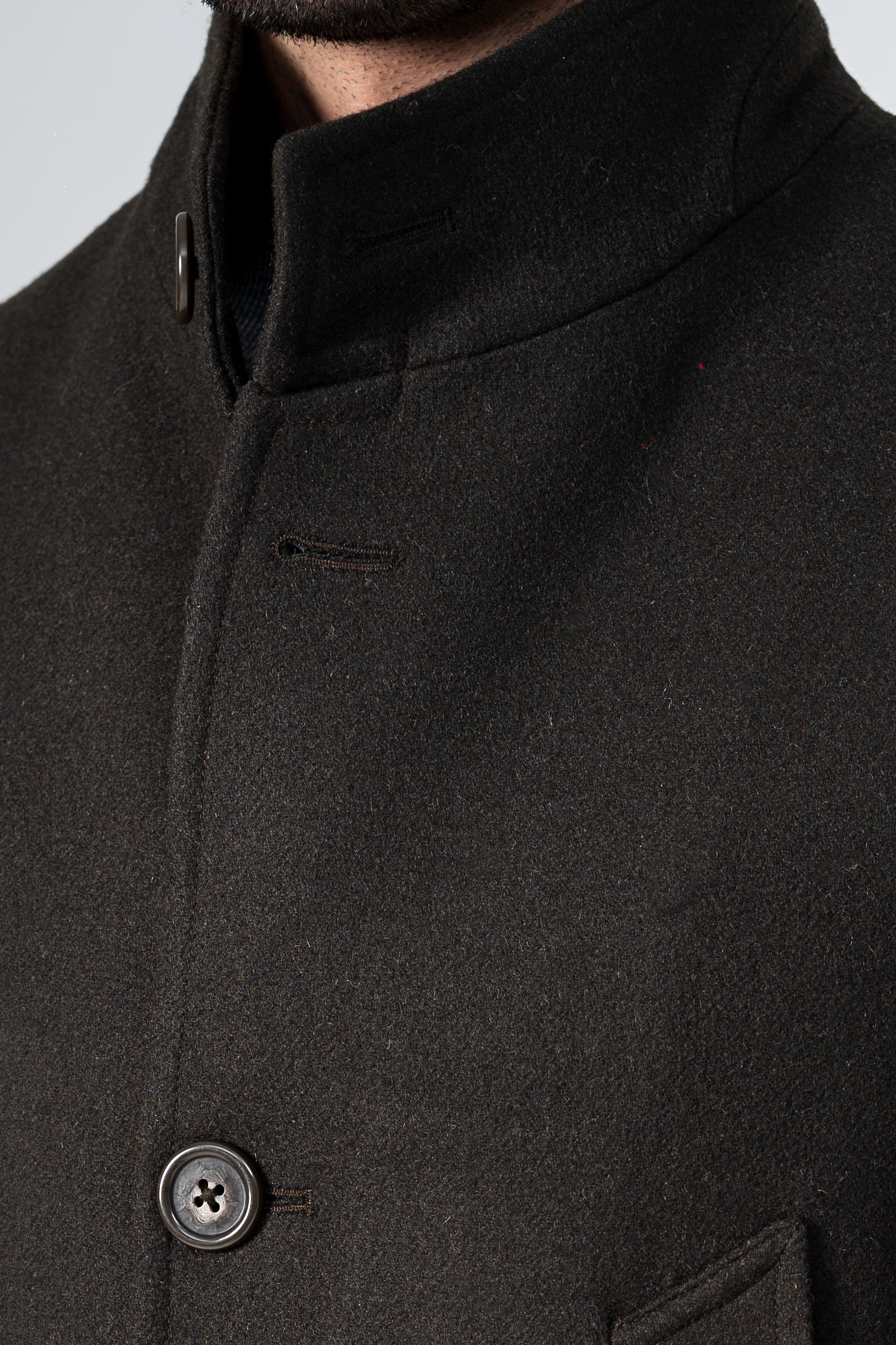 Dark olive wool coat close-up: stand collar with button and pocket flap