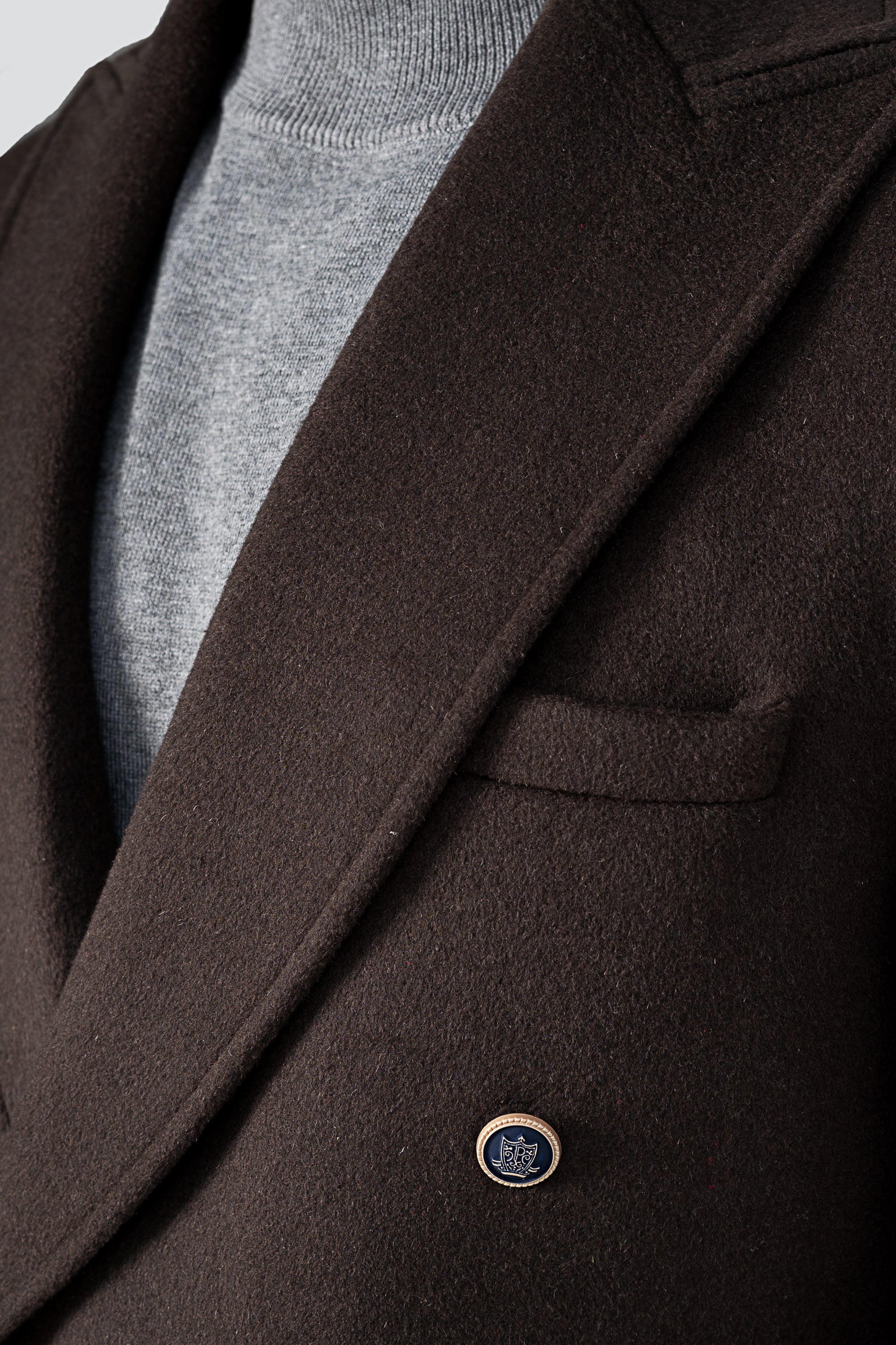 Dark brown wool long coat close-up, logo button and flap pocket detail