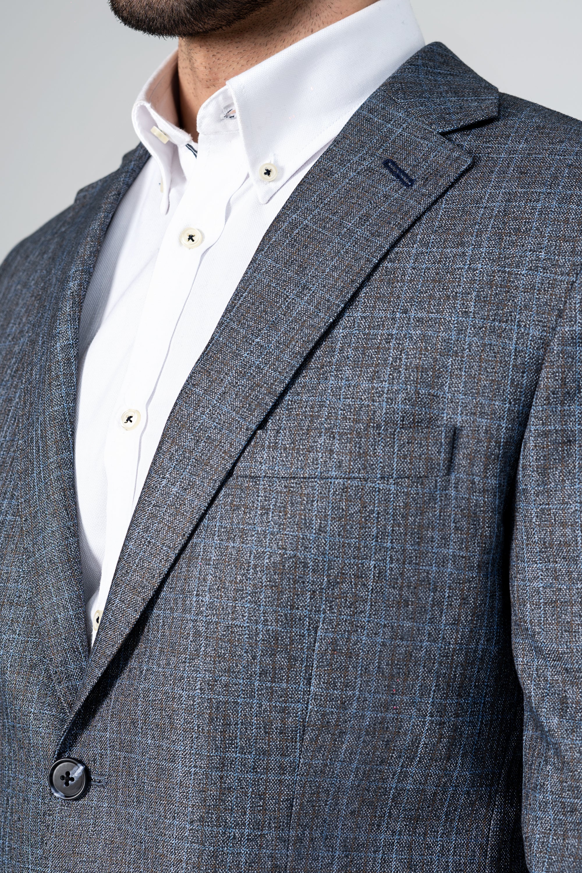 Grey-blue textured blazer close-up with notch lapels and button detail.