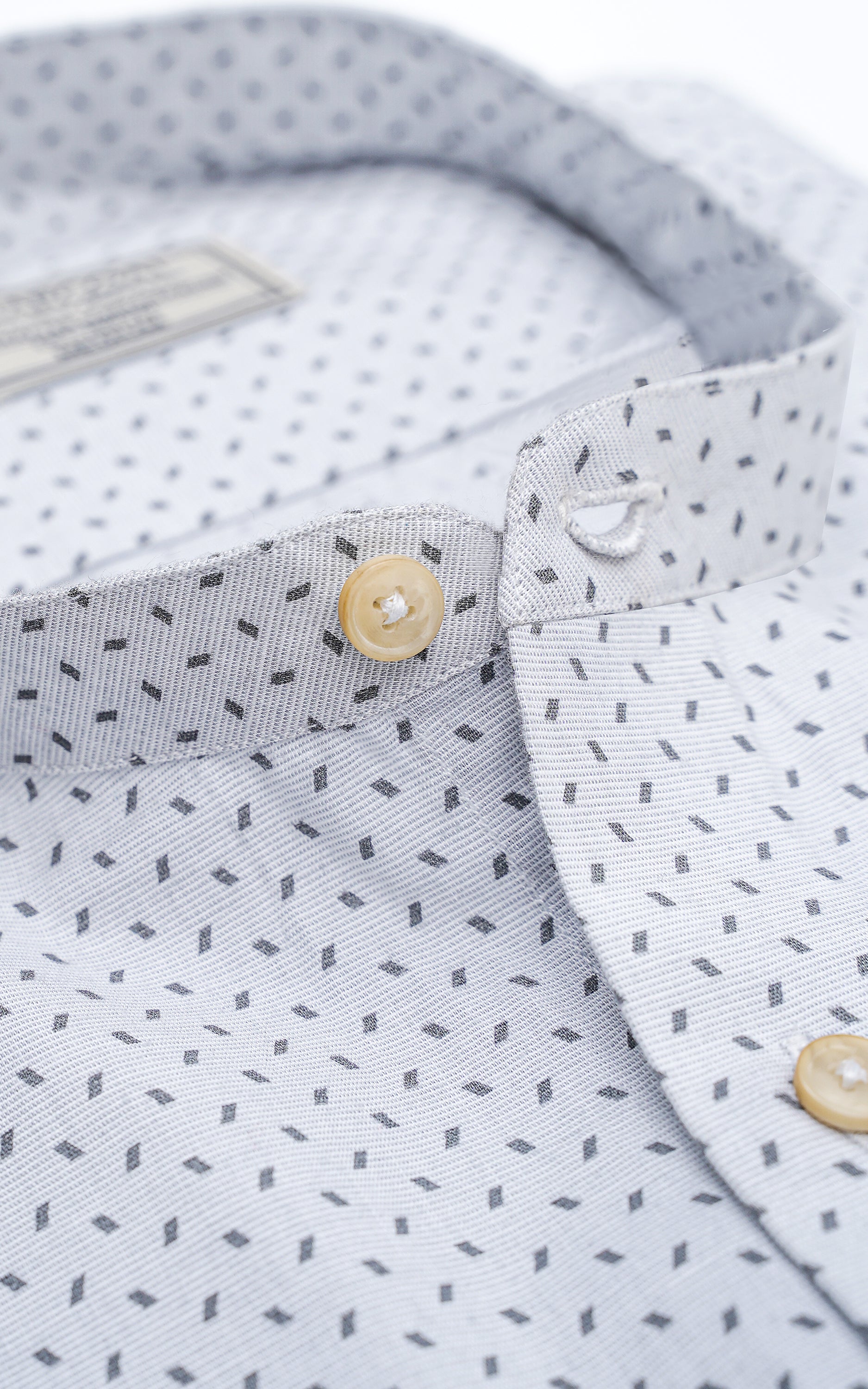 Light grey shirt close-up with geometric dot-and-rectangle print and buttoned placket