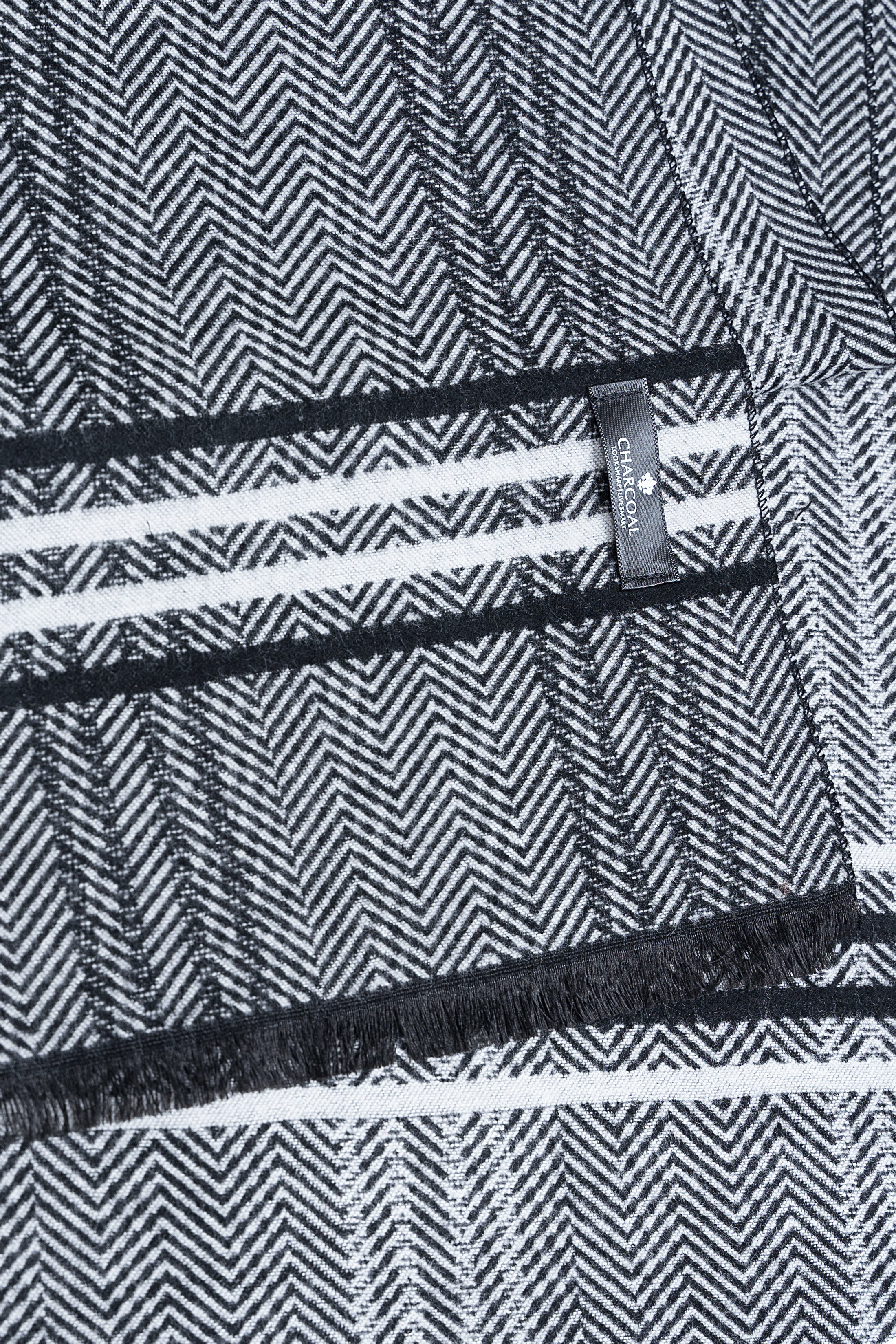 Herringbone scarf detail with dark striped bands and woven brand label