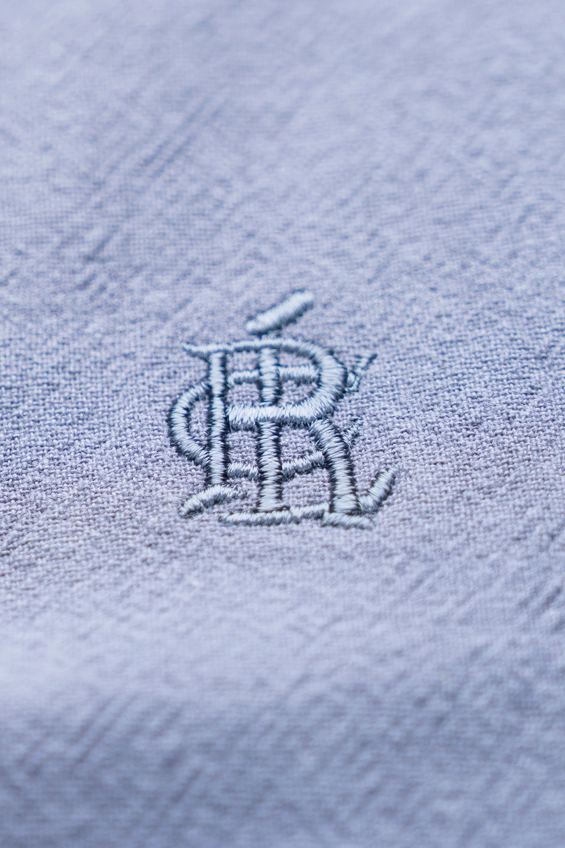 Grey shirt fabric with chest logo embroidery, detailed close-up