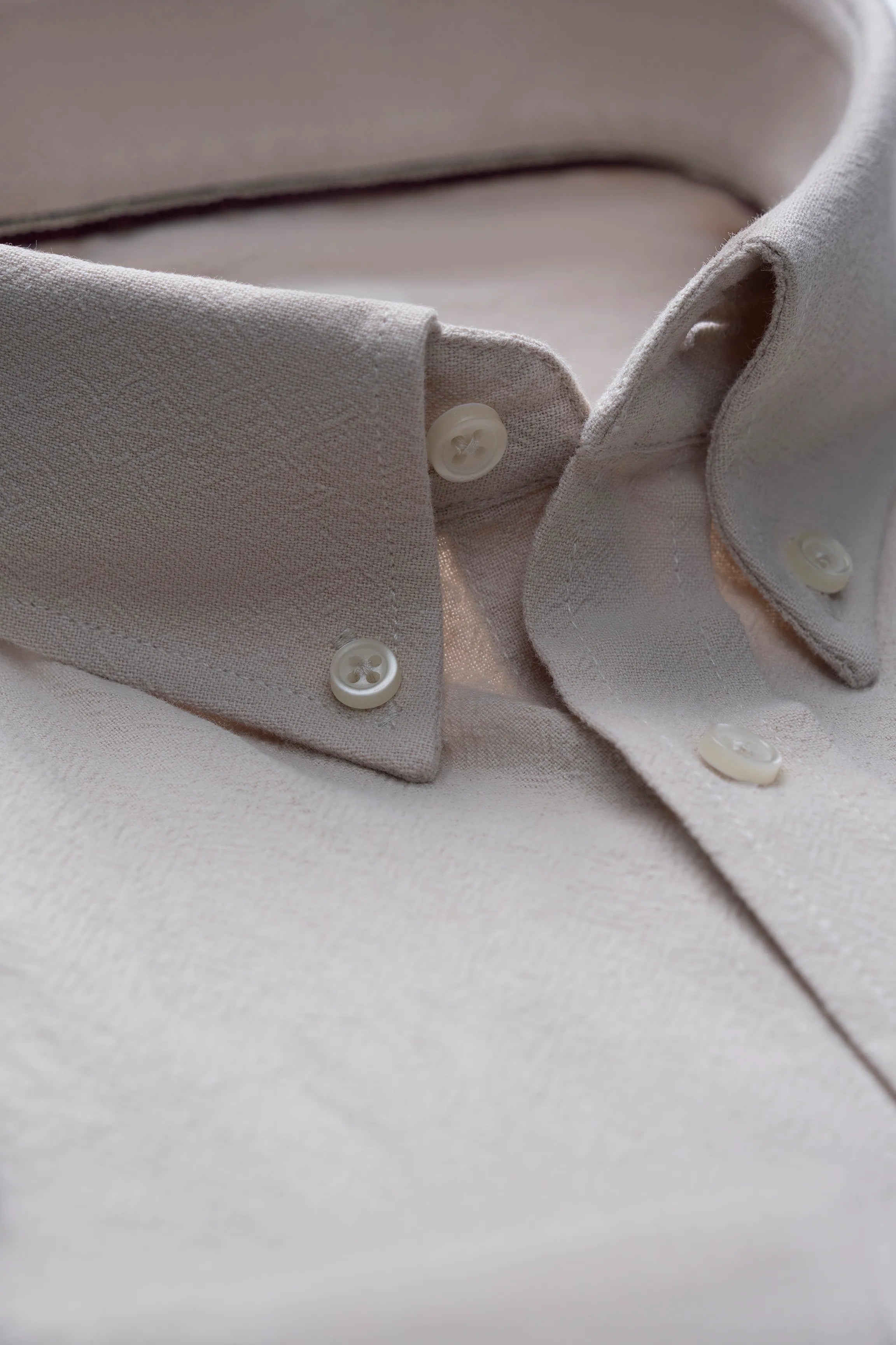 Beige button-up shirt showing collar, placket, and cuffs
