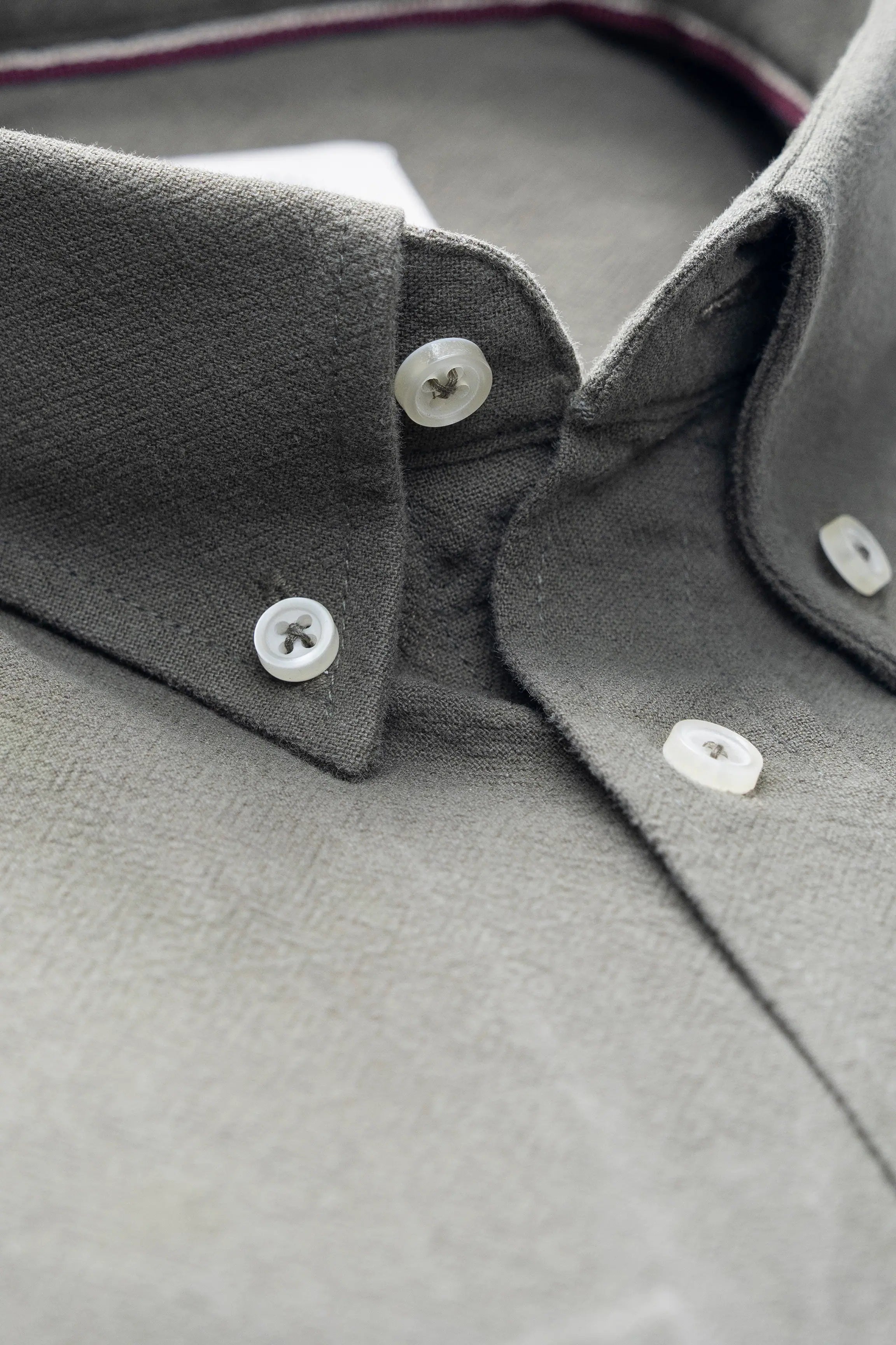 Dark gray shirt collar close-up with white buttons and stitched placket