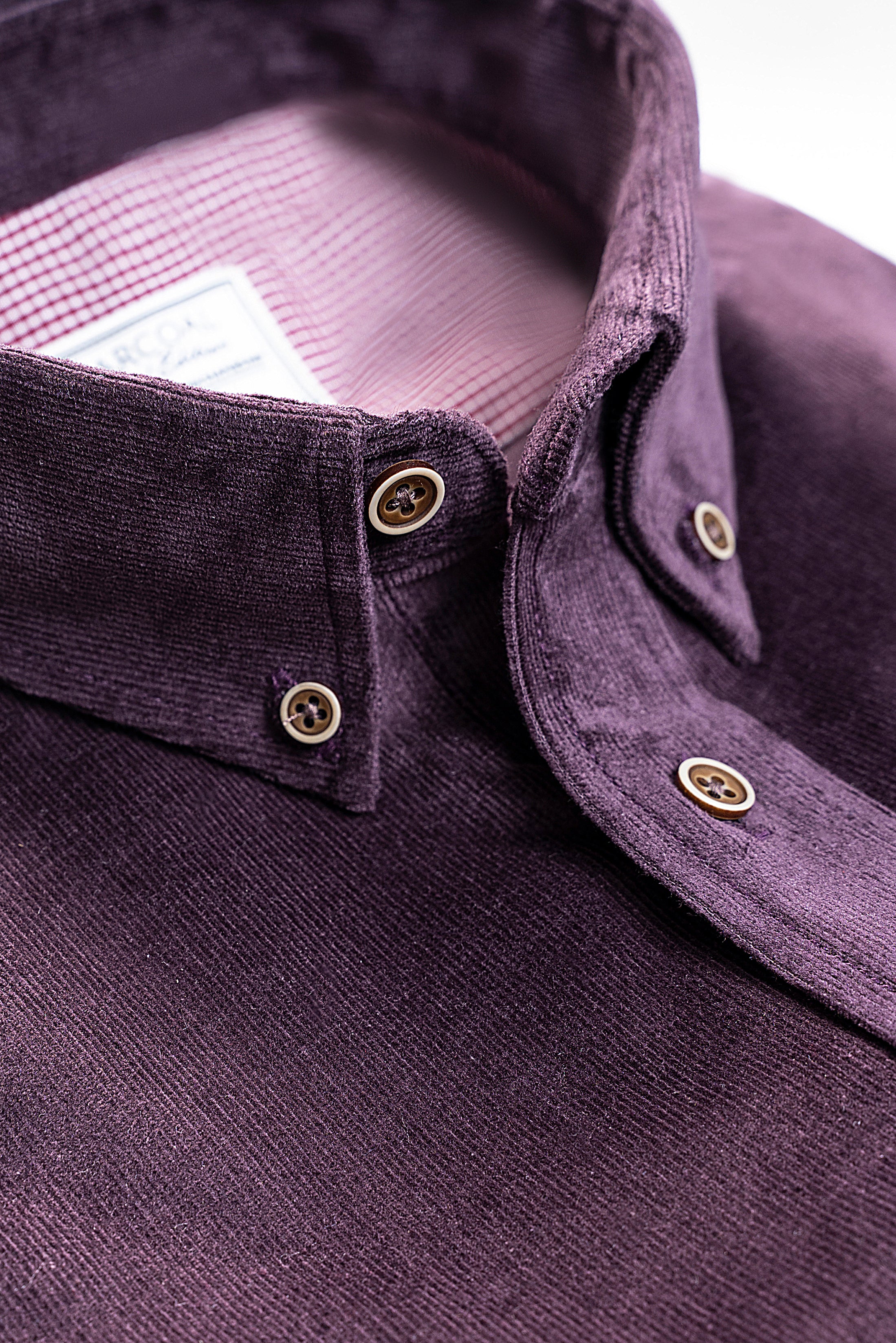 Corduroy shirt collar and button placket close-up in dark plum, gold-tone buttons