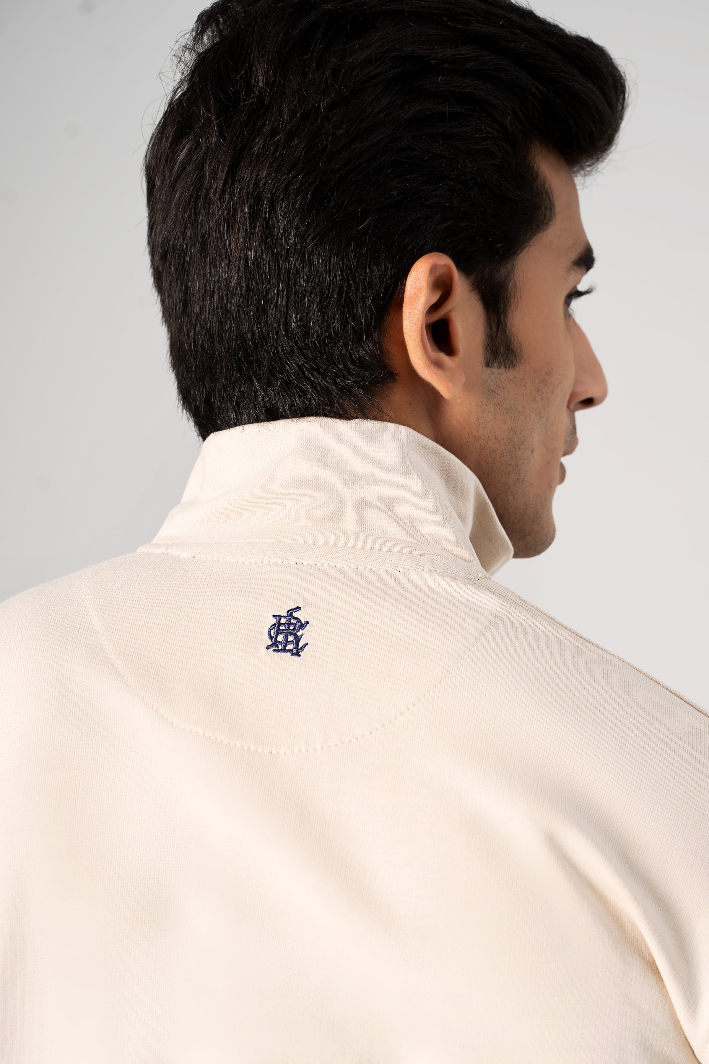Beige mock neck sweatshirt collar with small emblem at the back