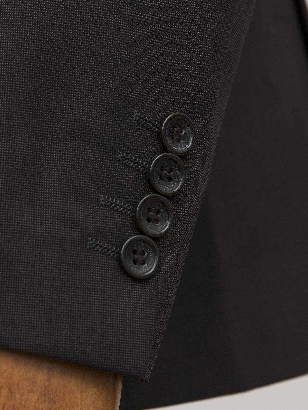 Dark suit blazer sleeve cuff with four buttons and textured fabric weave