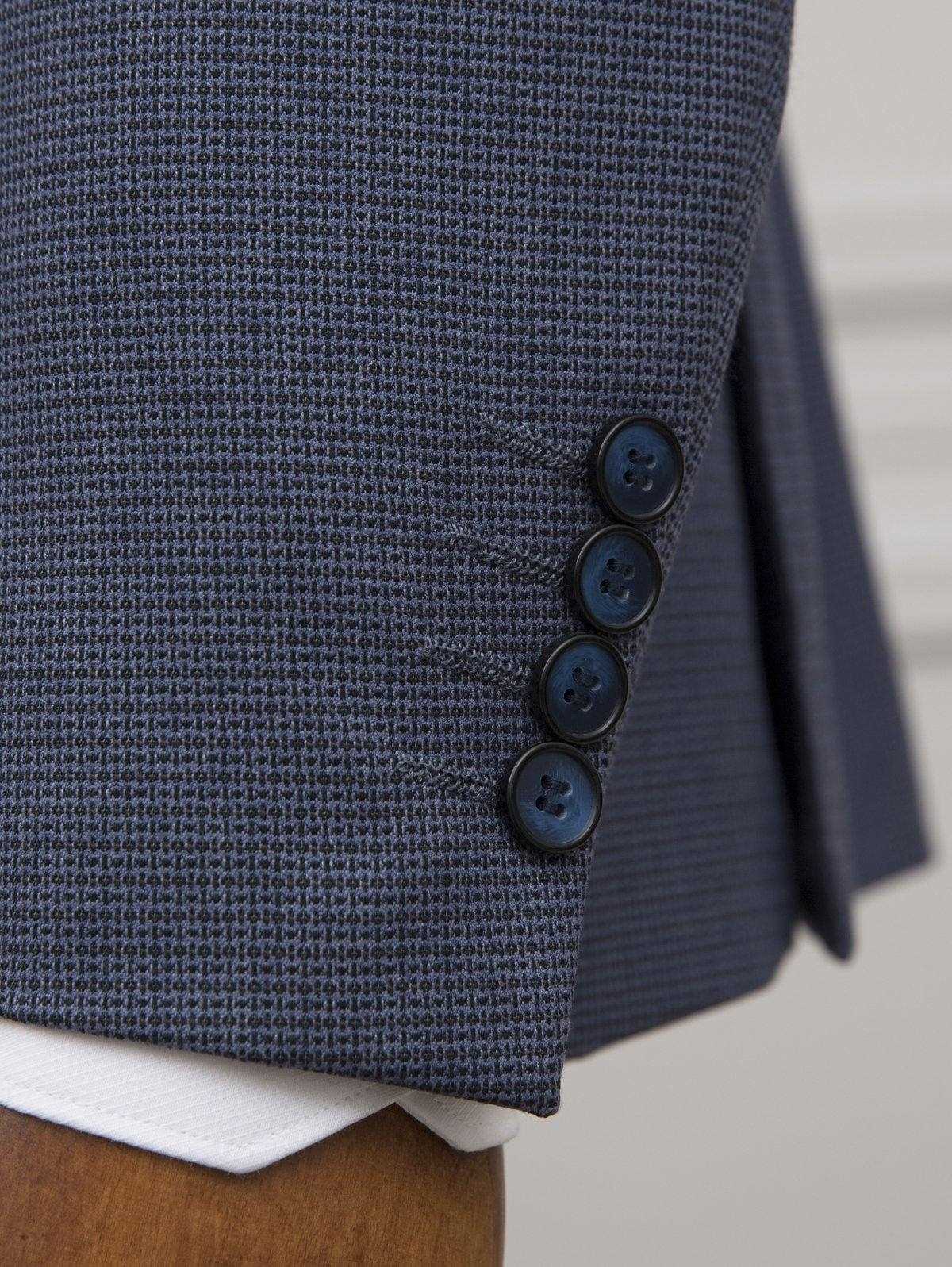 Blue suit jacket sleeve cuff with four dark buttons and textured fabric detail