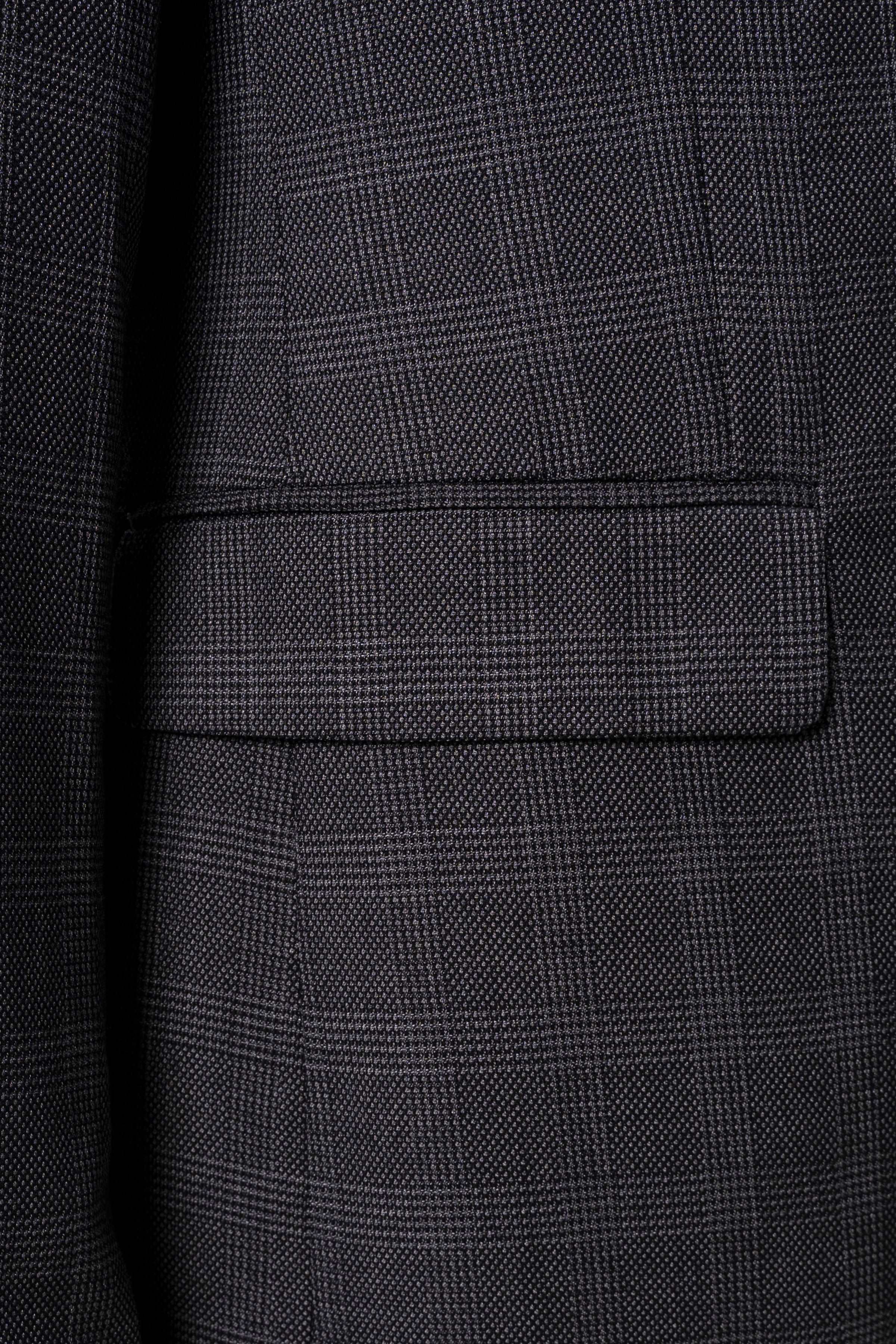 Dark grey suit jacket cuff and front pocket with subtle plaid texture