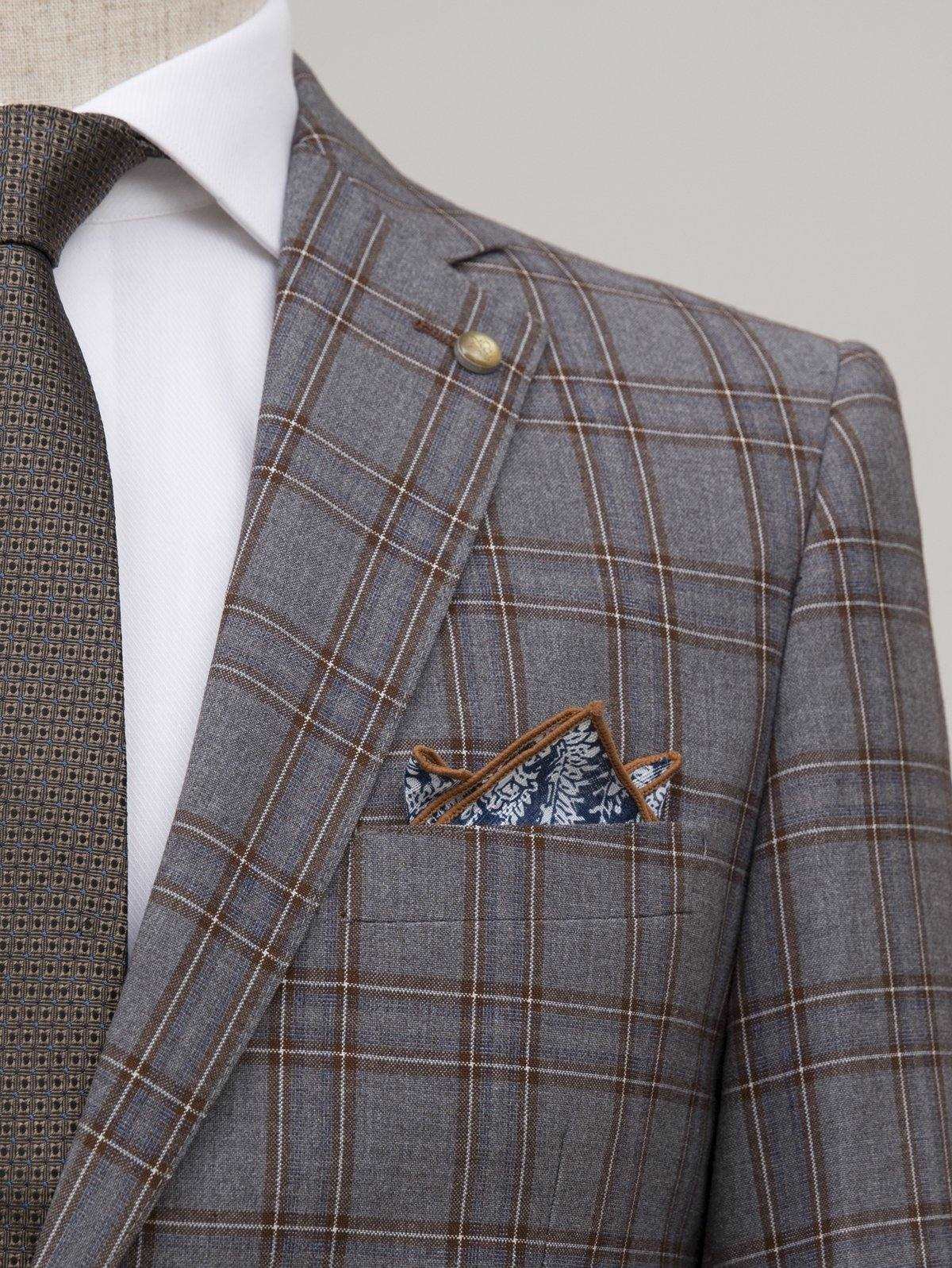 Grey plaid blazer lapel with pocket square in patterned blue fabric