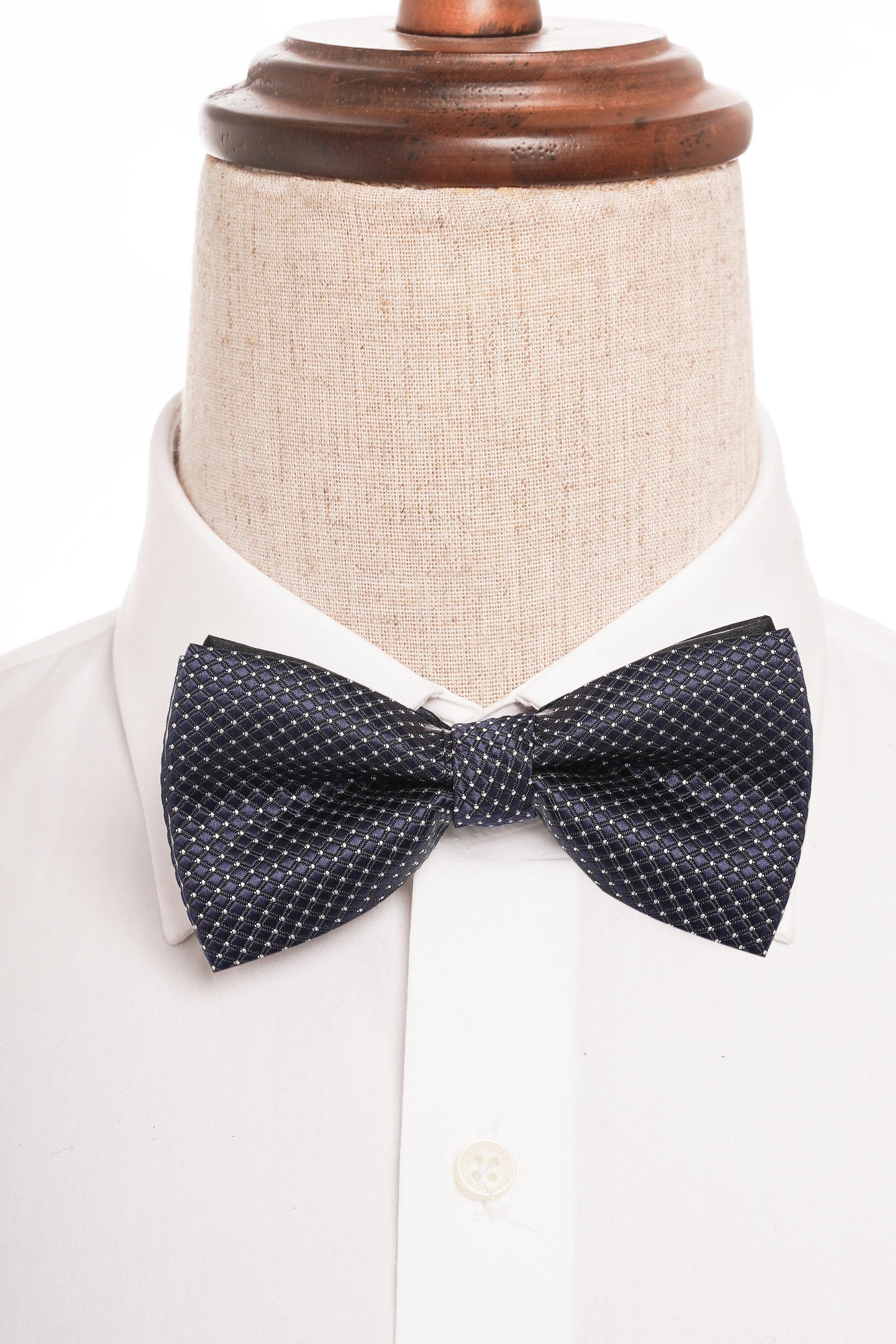 Dark navy bow tie with white micro-dots, worn on white shirt collar