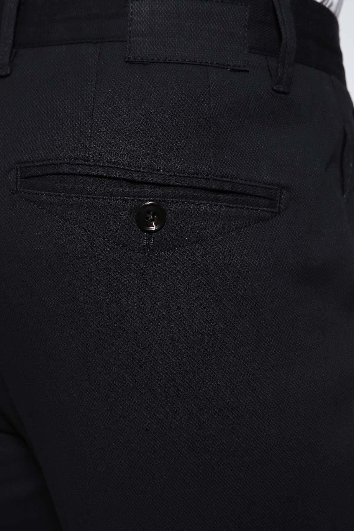 Black slim-fit pants close-up: cross pocket with button and stitched panel