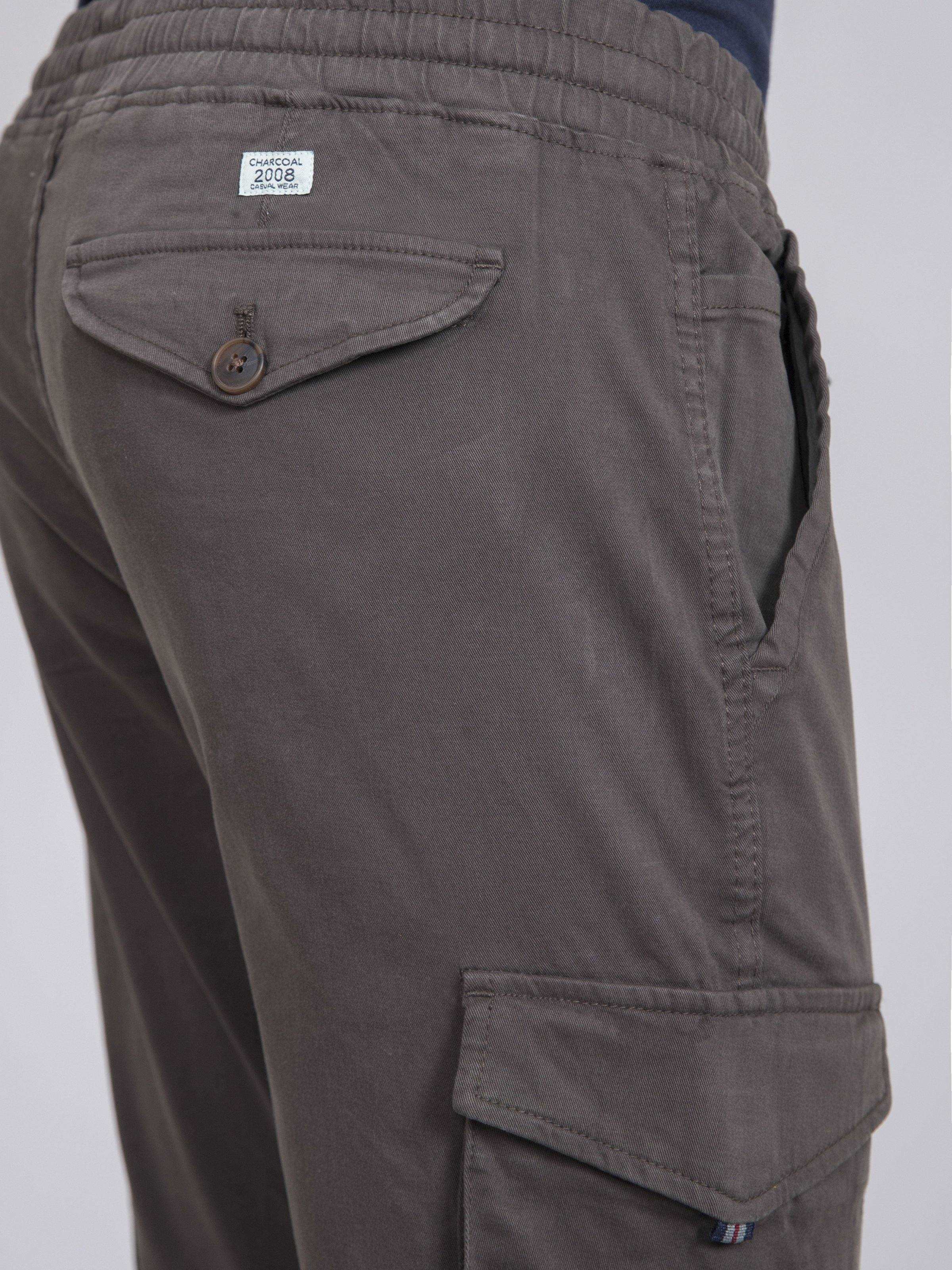 Close-up of dark gray cargo jogger trousers: back pocket flap and side cargo pocket