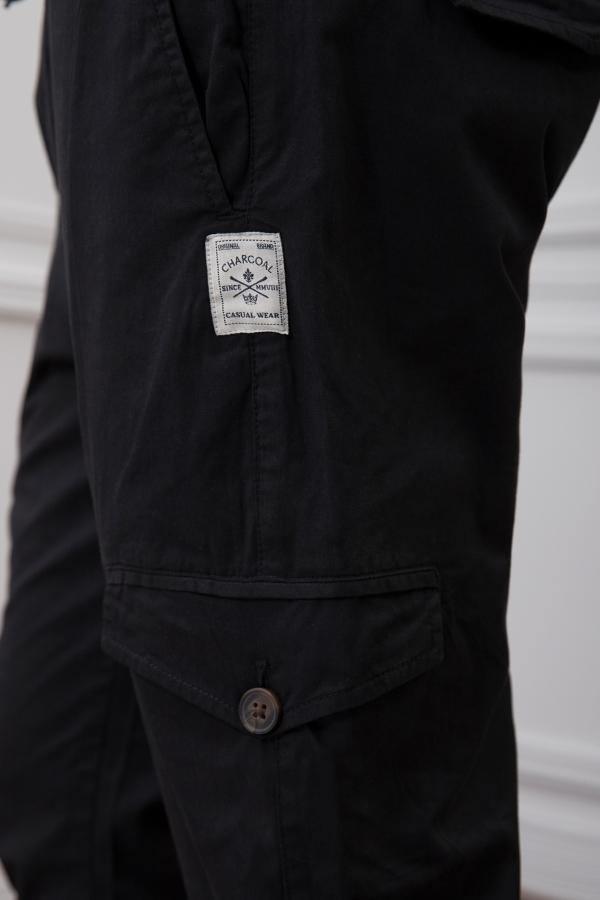 Black cargo trouser close-up with fabric label and flap pocket with button