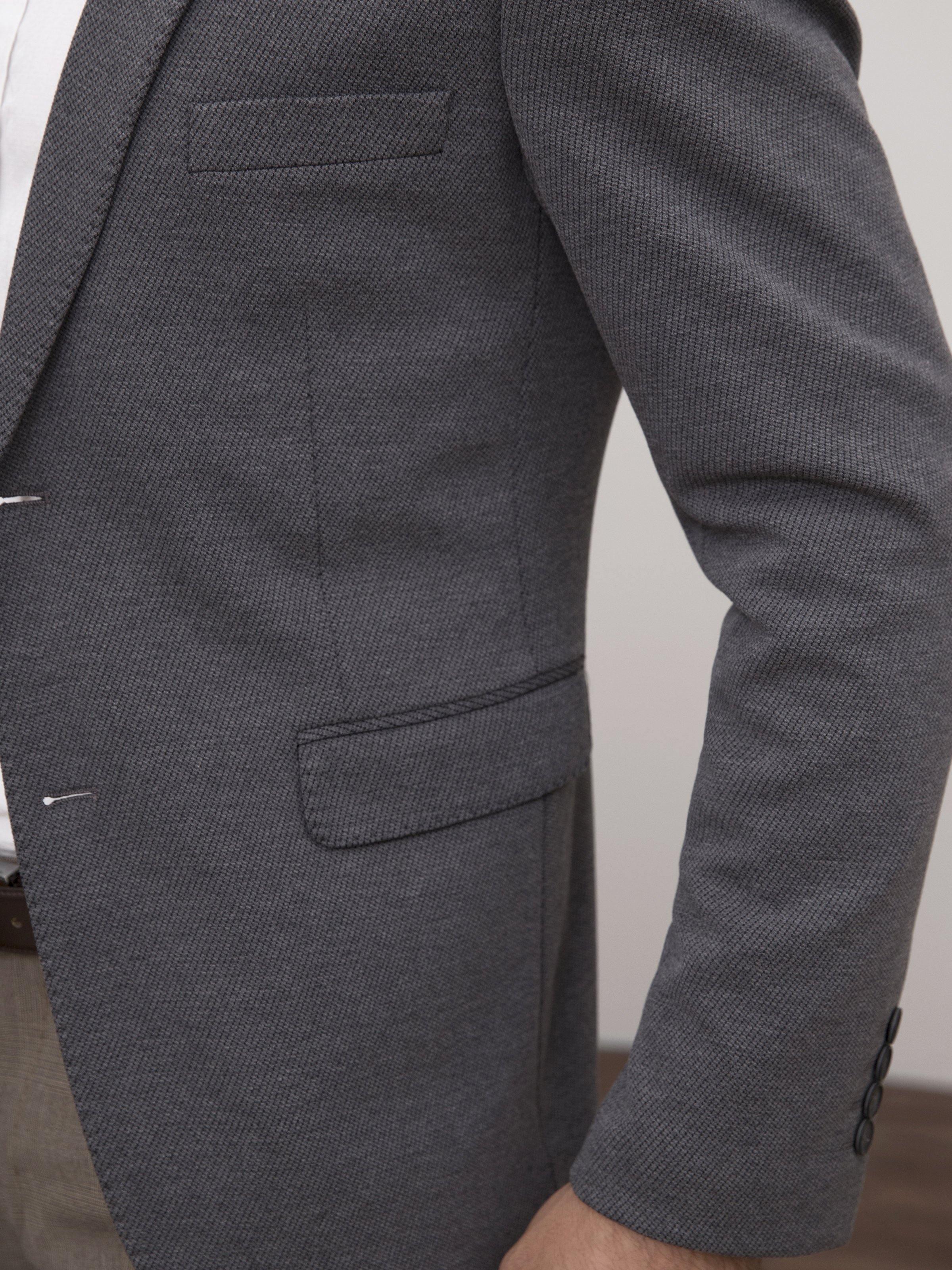 Grey casual coat close-up of sleeve cuff and side pocket with button detail