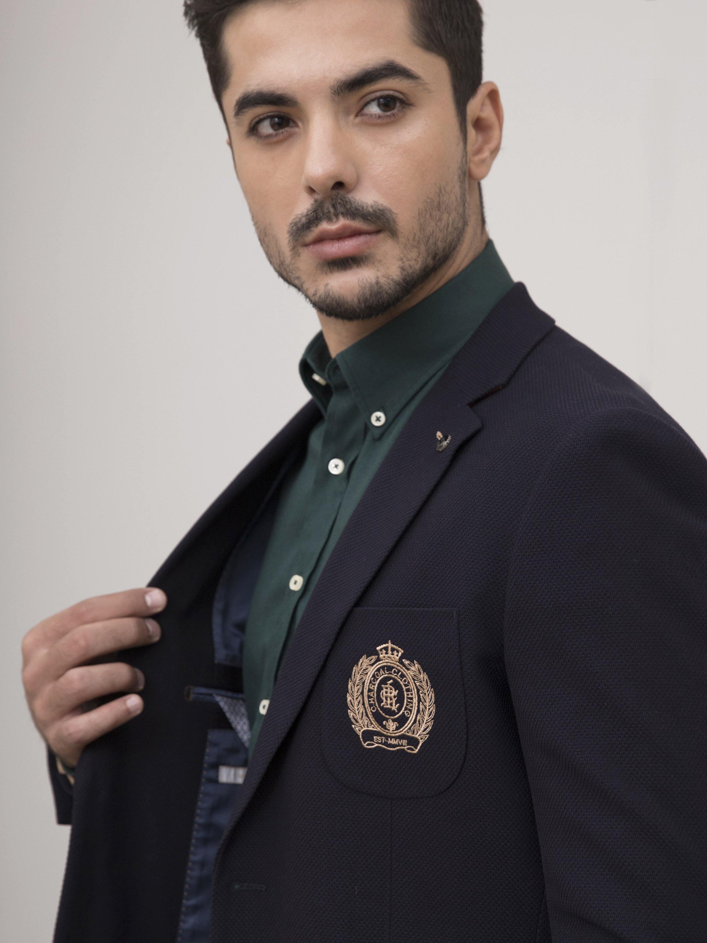 Navy slim-fit casual coat close-up with crest patch, lapel pin, and chest flap pocket