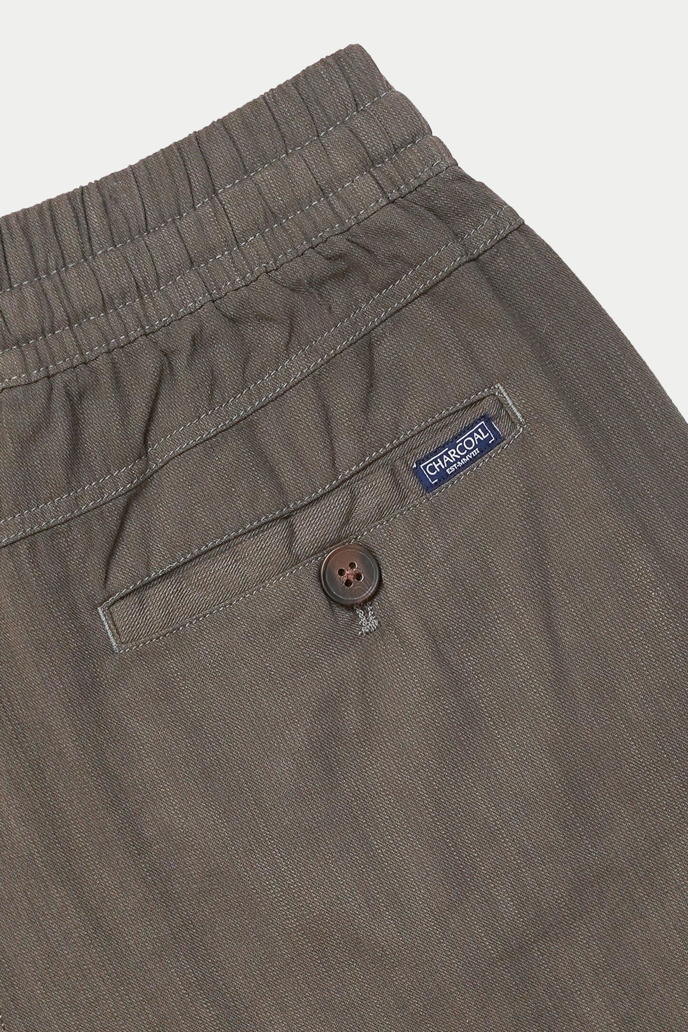 Grey jogger trousers with button fly, side pocket, and brand label near waistband