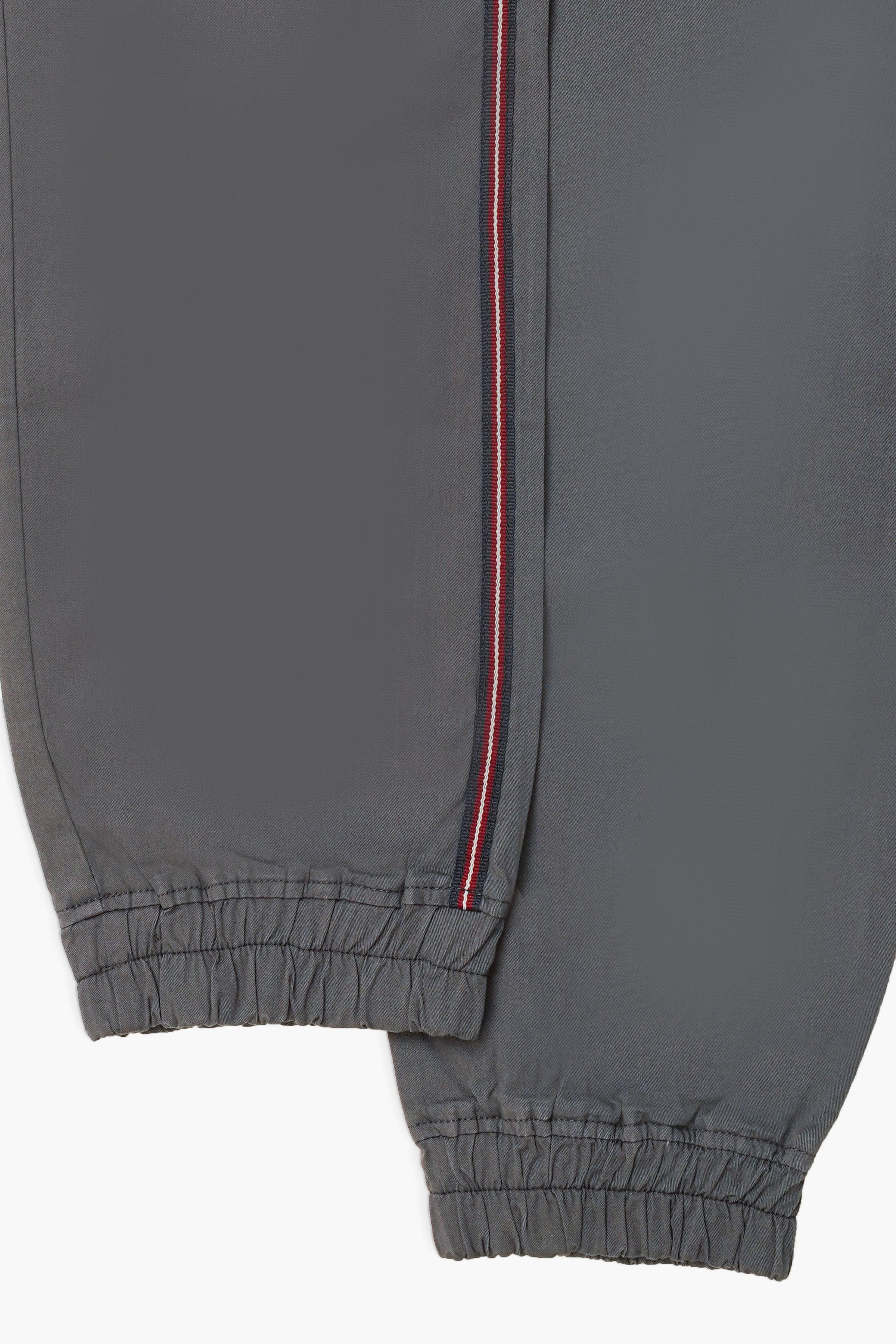 Grey jogger trousers with red side stripe and elastic ankle cuffs, full-length view