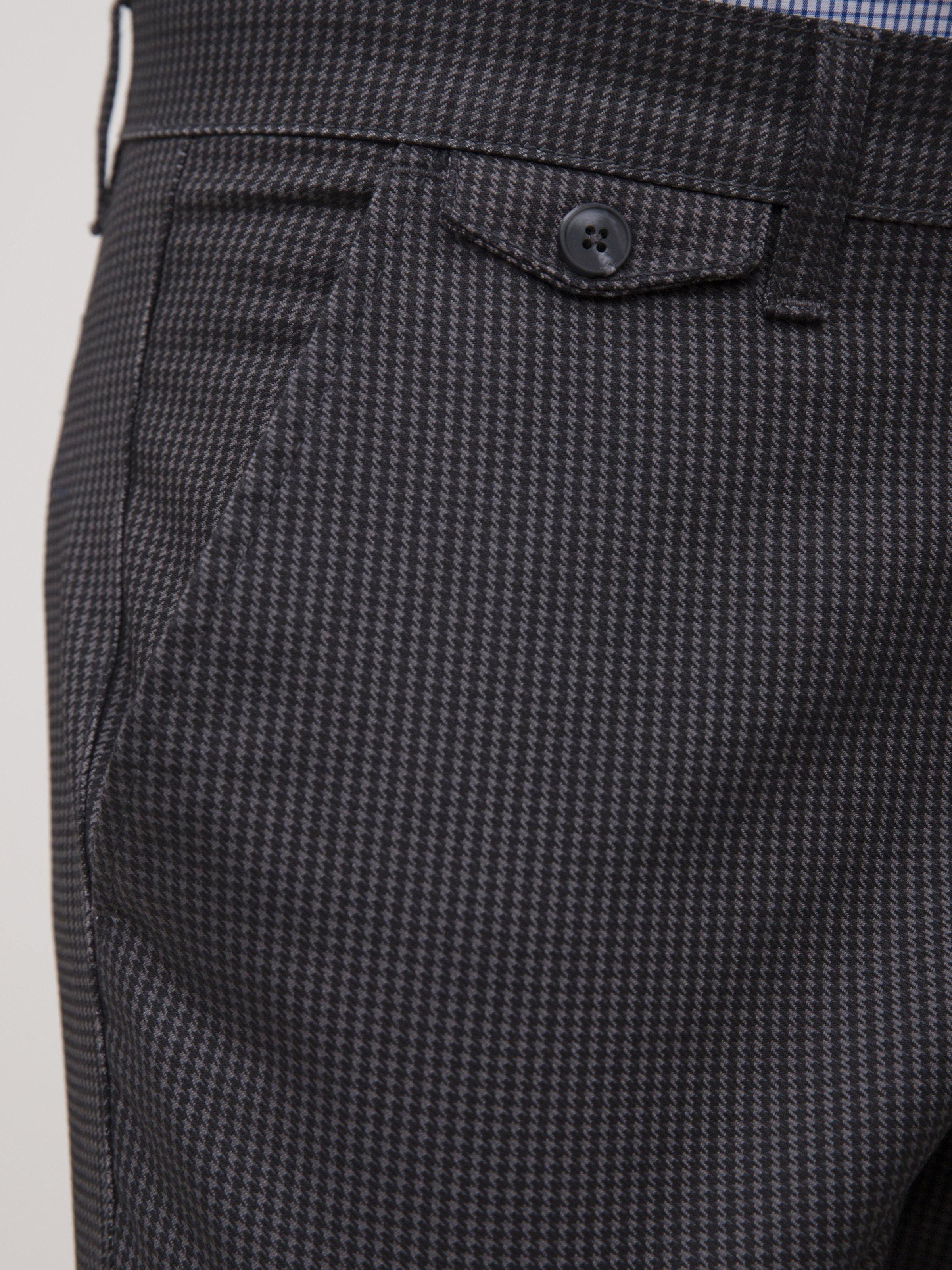 Black houndstooth pants with welt pocket flap and front button detail