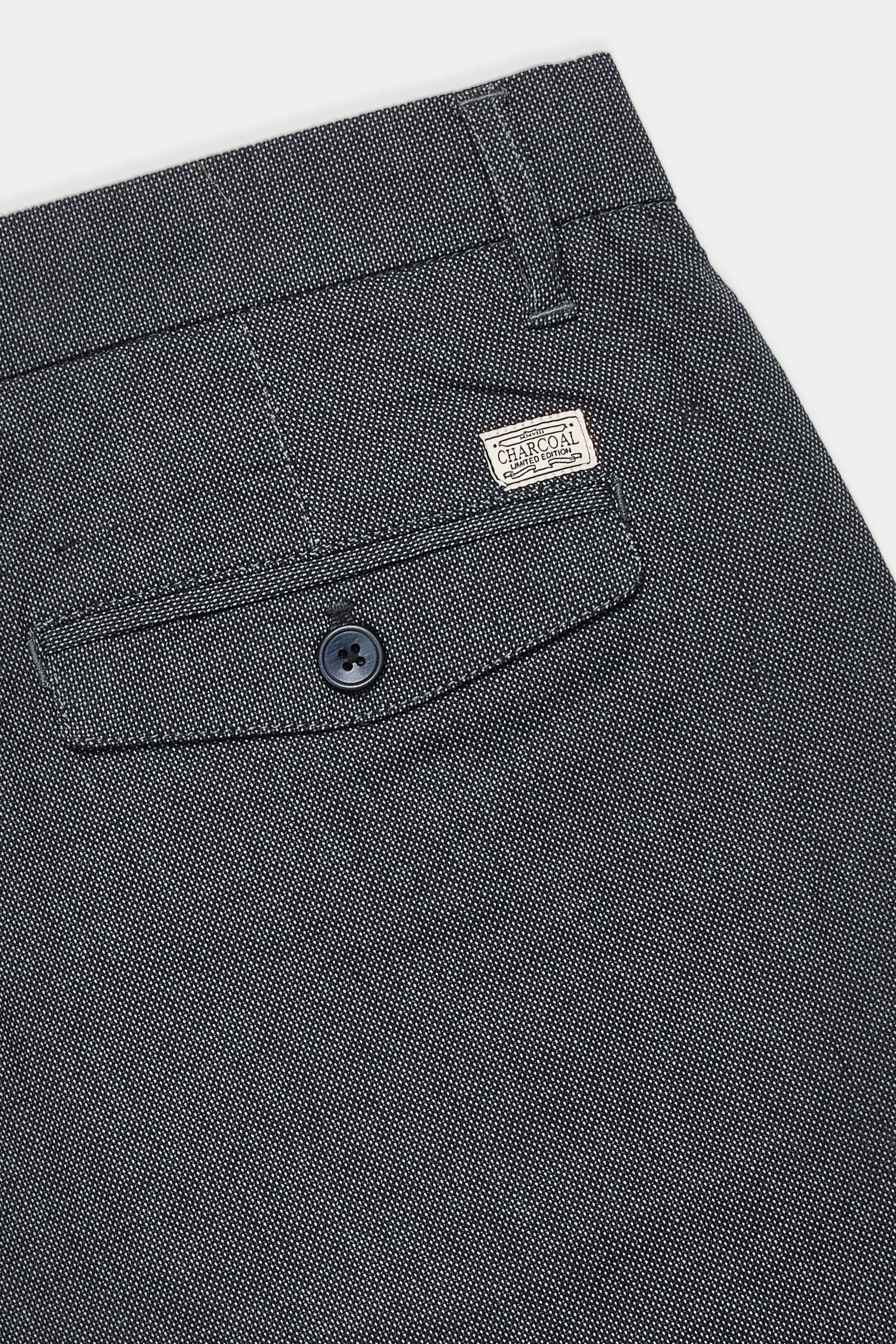 Casual pants waistband close-up with brand label, belt loops, and button detail.
