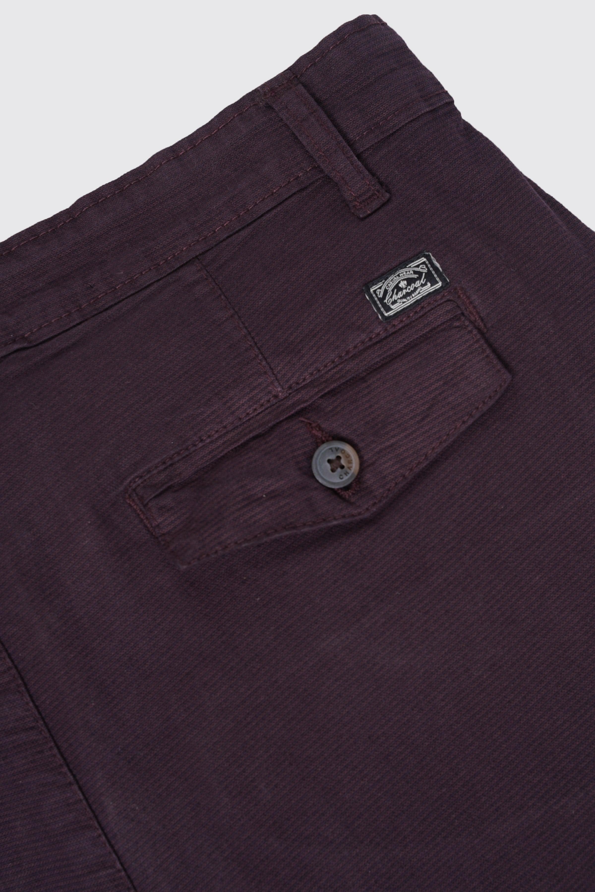 Maroon casual pants with brand patch, belt loops, and button fly, close-up