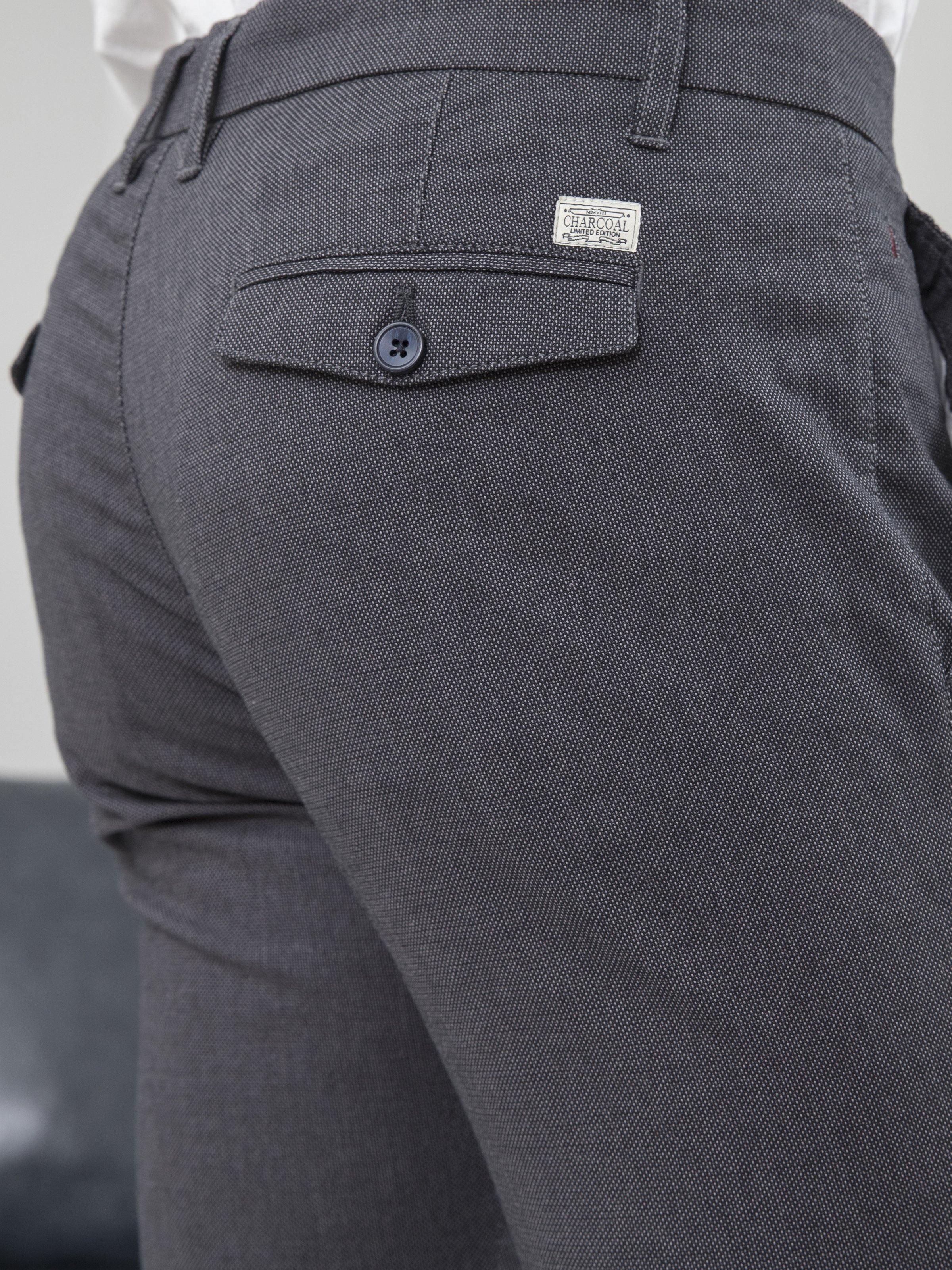 Blue-black slim fit pants close-up of back pocket and button logo patch